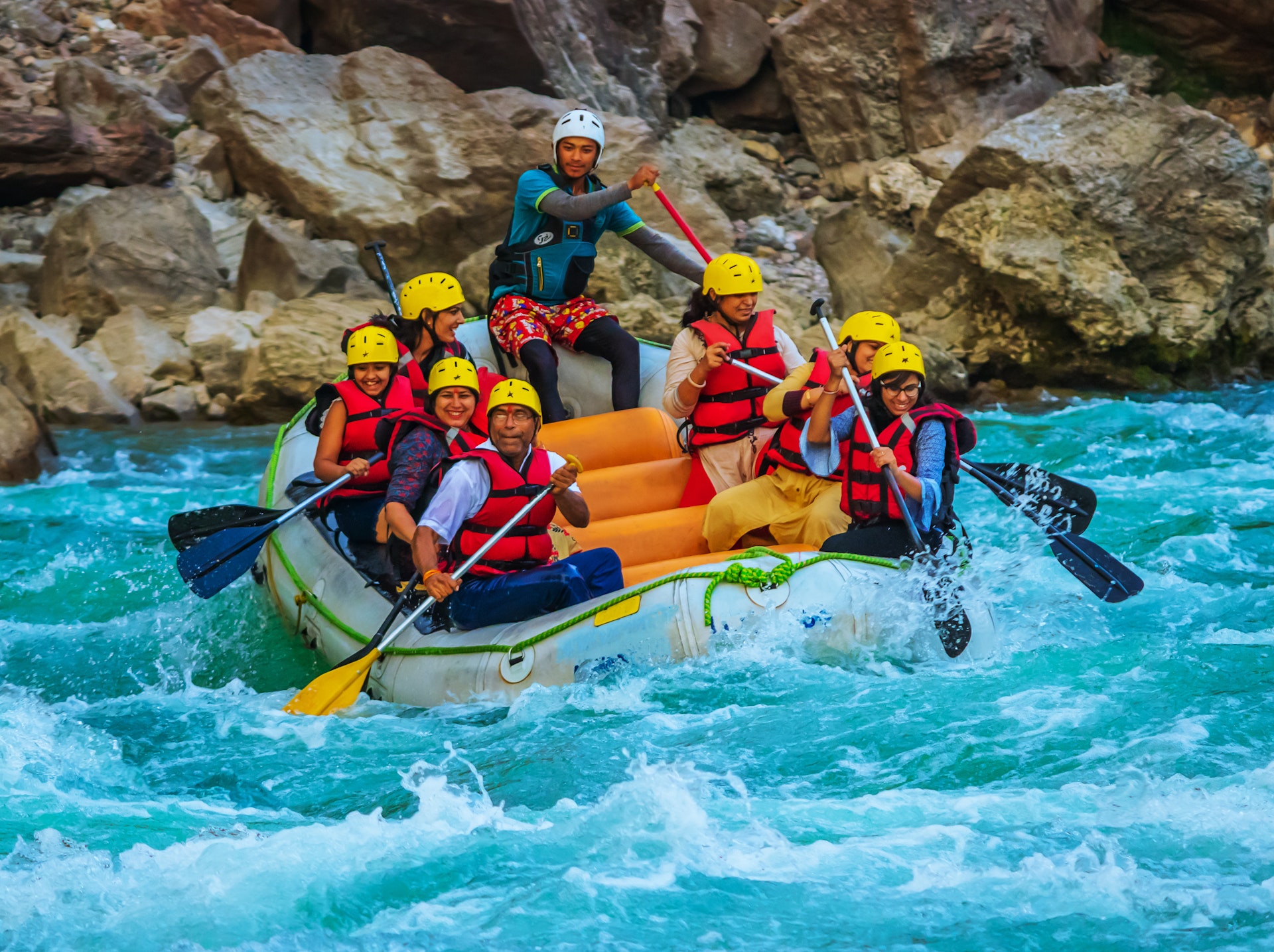 People smiling as they face the challenge of white water rapids in a small boat