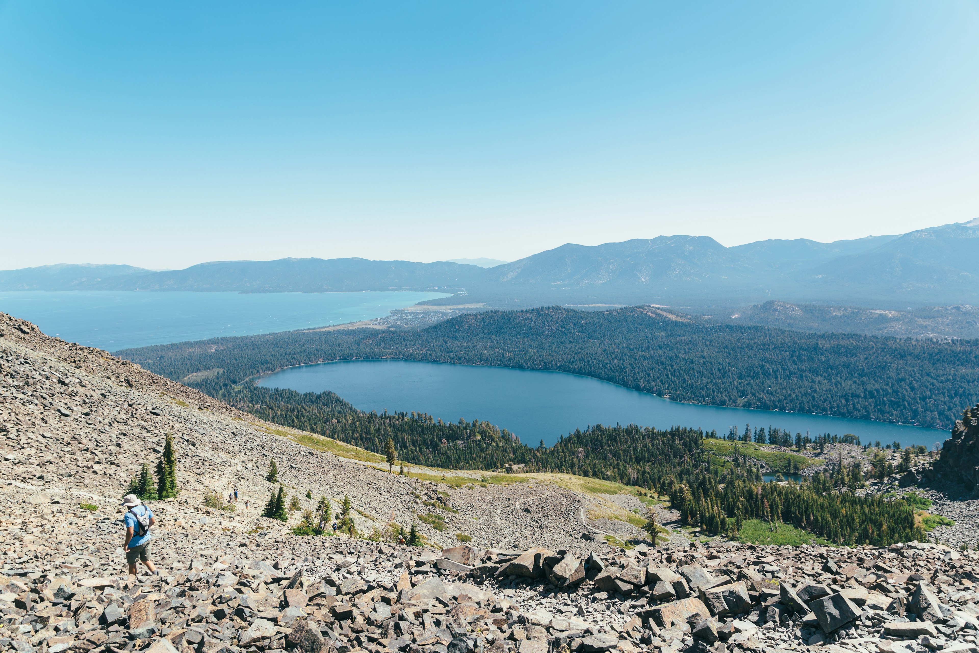 A hiker on a steep rocky path above a lake