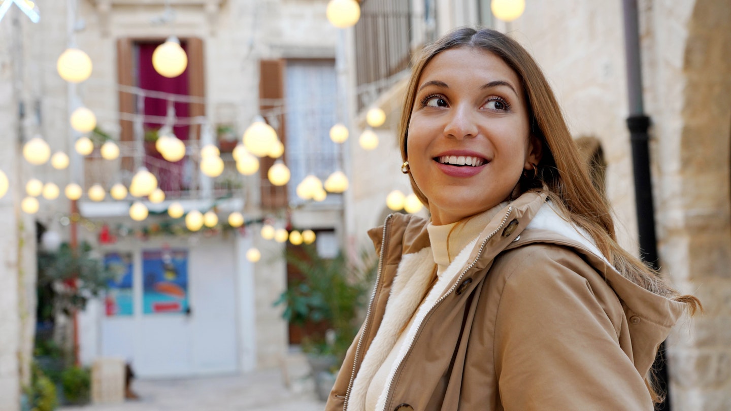 Christmas vibes. Close-up of winter woman walking between alleys decorated with lights in historic town on evening.; Shutterstock ID 2222544341; GL: 65050; netsuite: Online Editorial; full: When to go Puglia; name: Bailey Freeman
2222544341