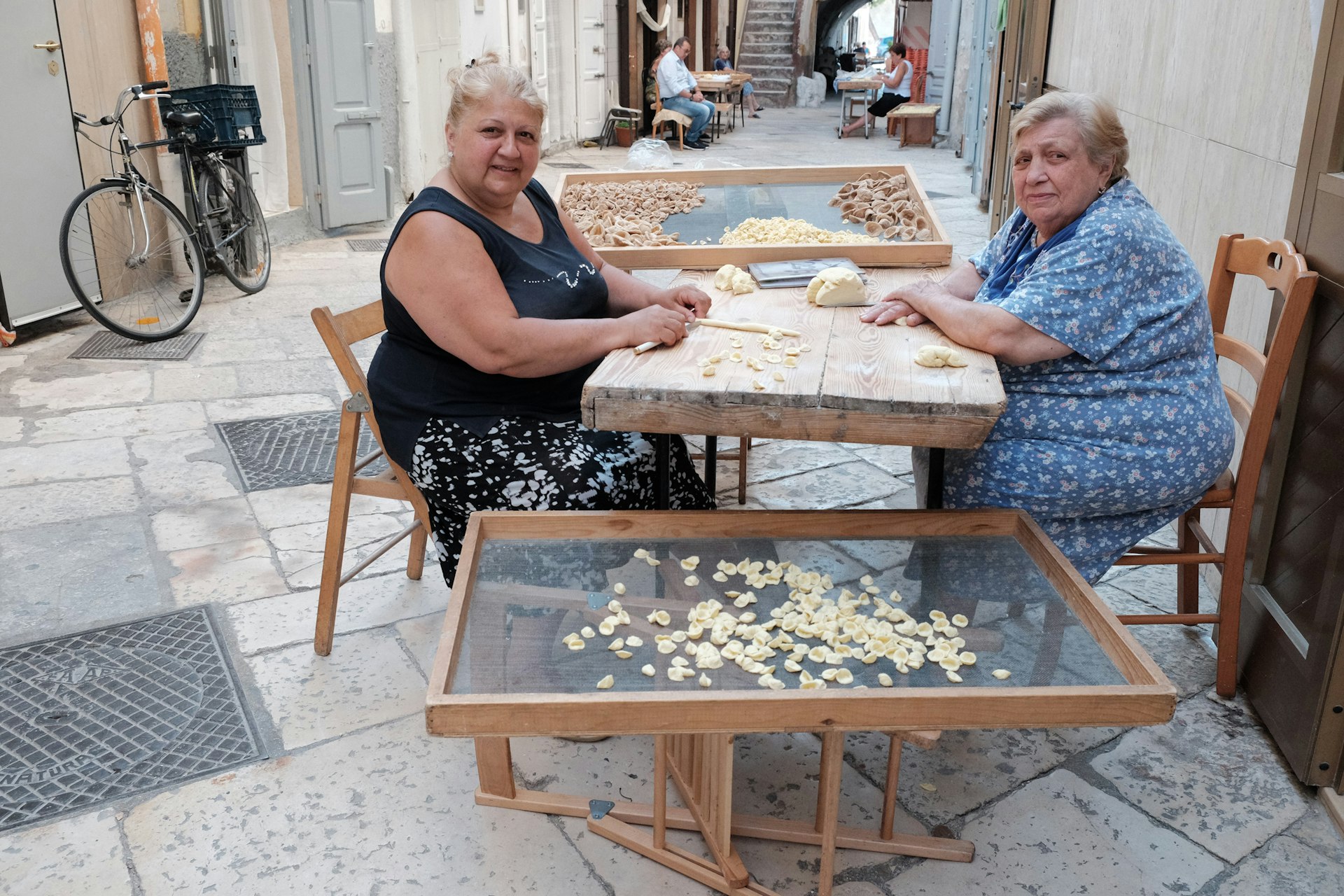 Women working at a table in the street making pasta, Bari, Puglia, Italy