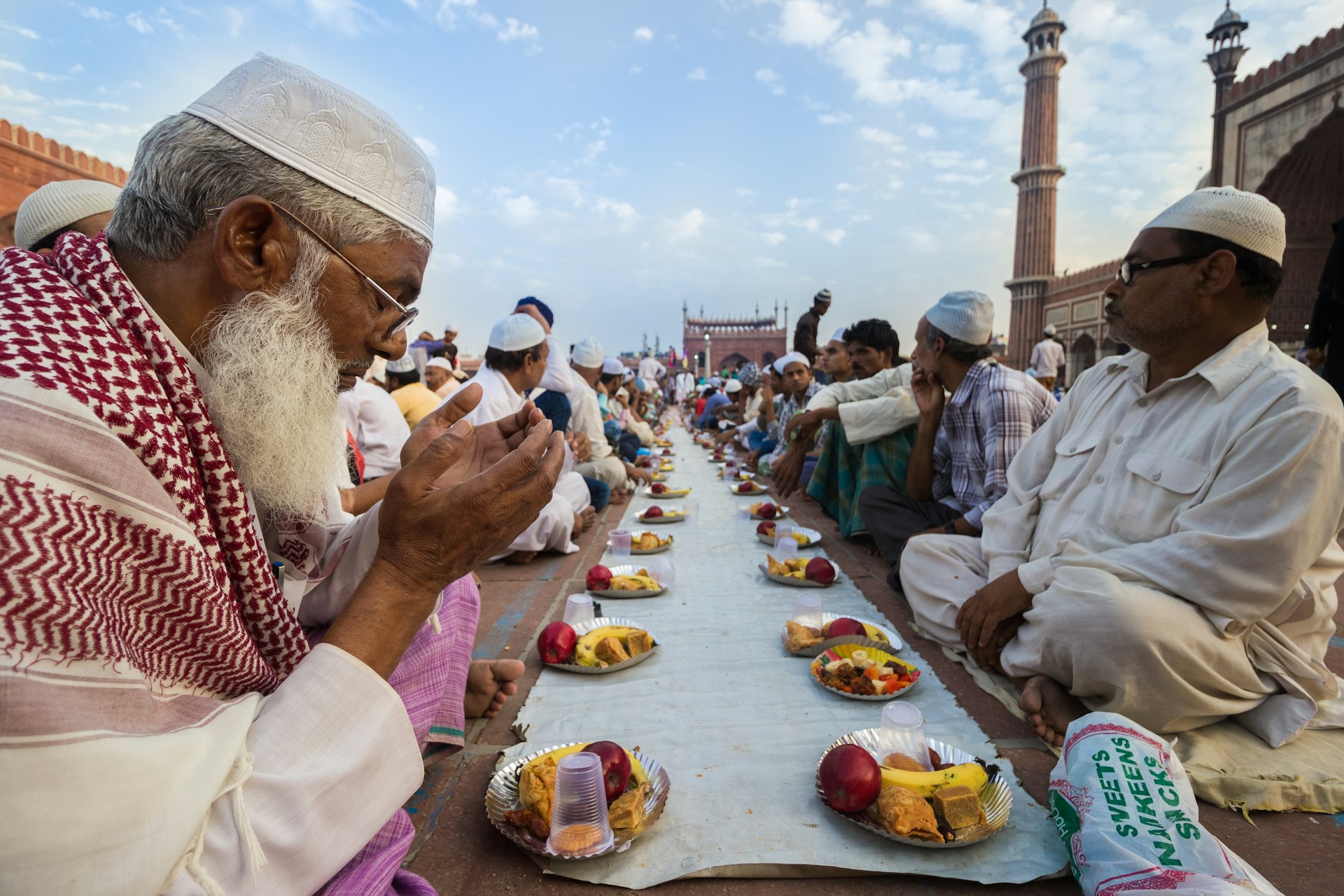 Men sit at a communal table in a square in India awaiting the breaking of the fast