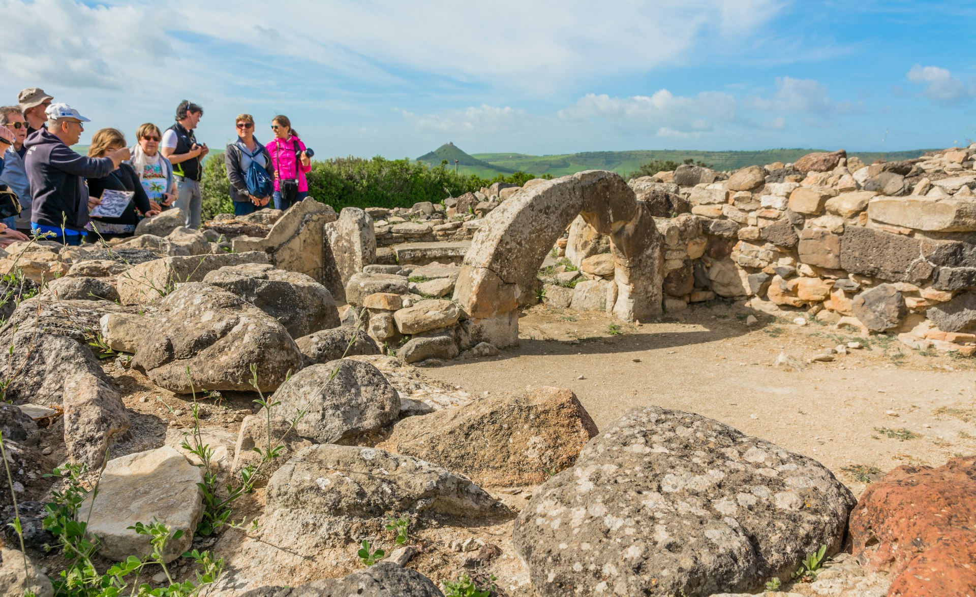 A guide and visitors at Nuraghe Su Nuraxi archaeological site in Sardinia