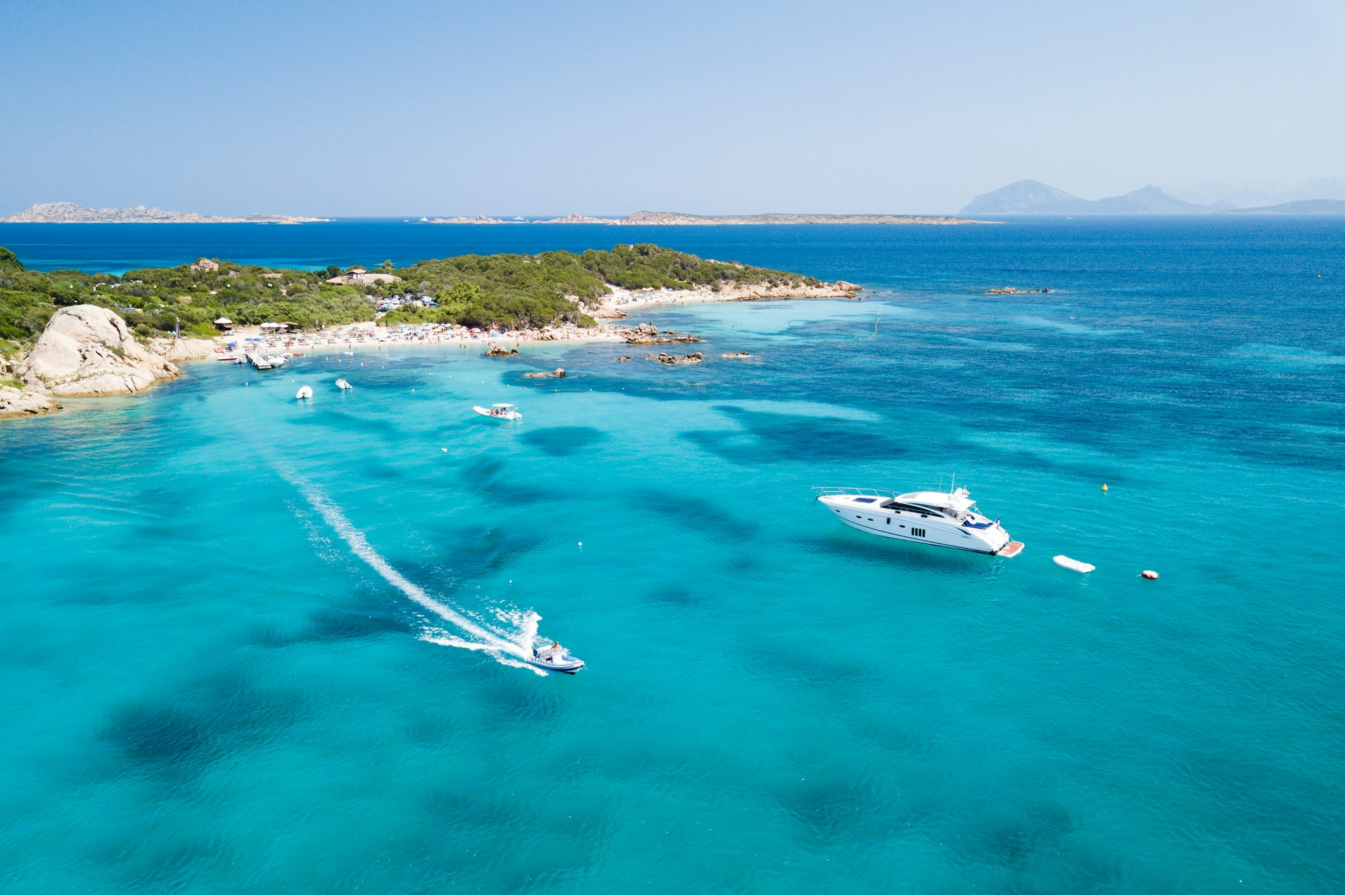Aerial of two boats sailing in a transparent and turquoise Mediterranean sea on the Emerald Coast (Costa Smeralda) in Sardinia.