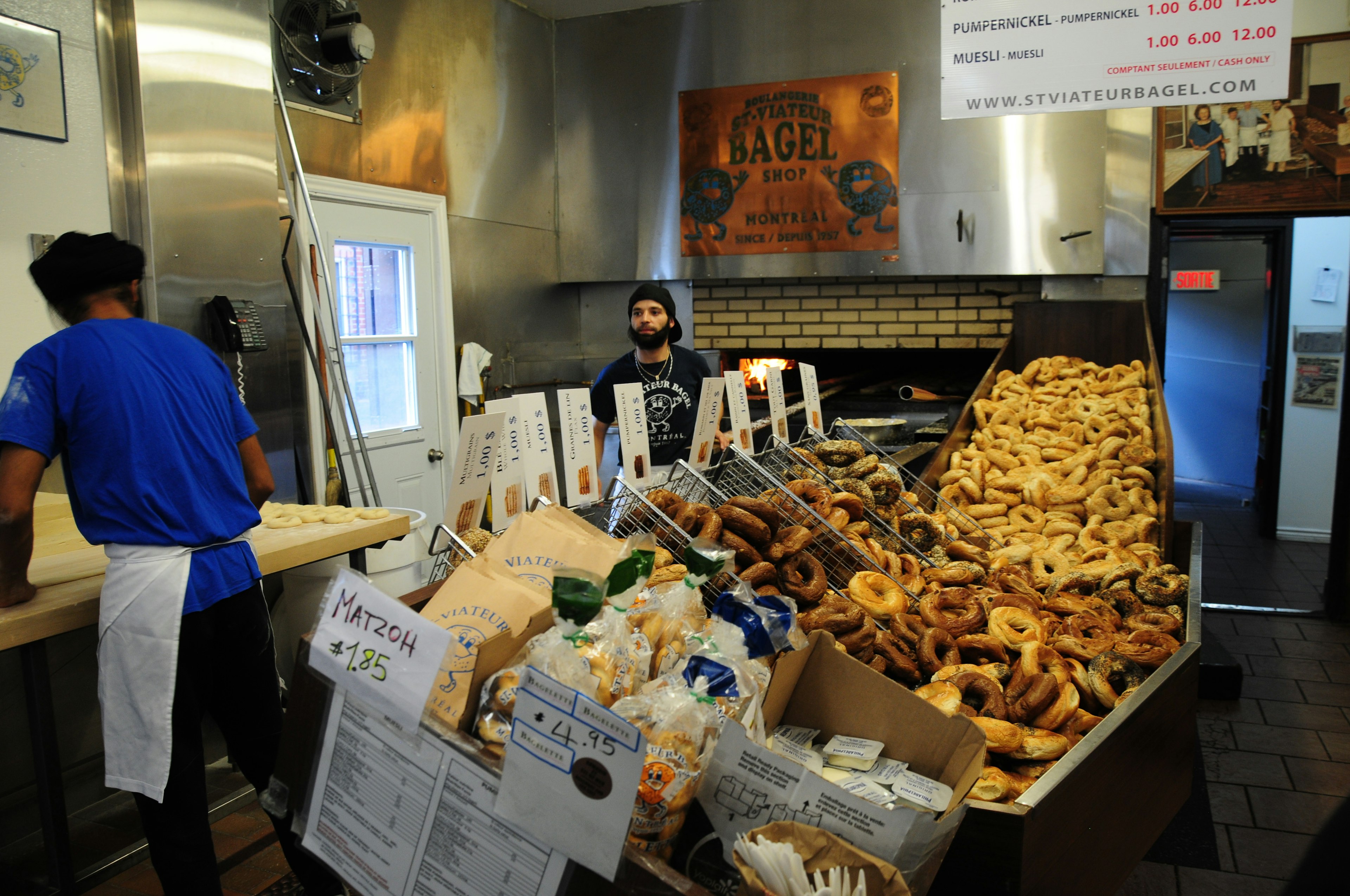 Workers with piles of baked goods in Boulangerie St-Viateur Bagel Shop, Montréal, Canada