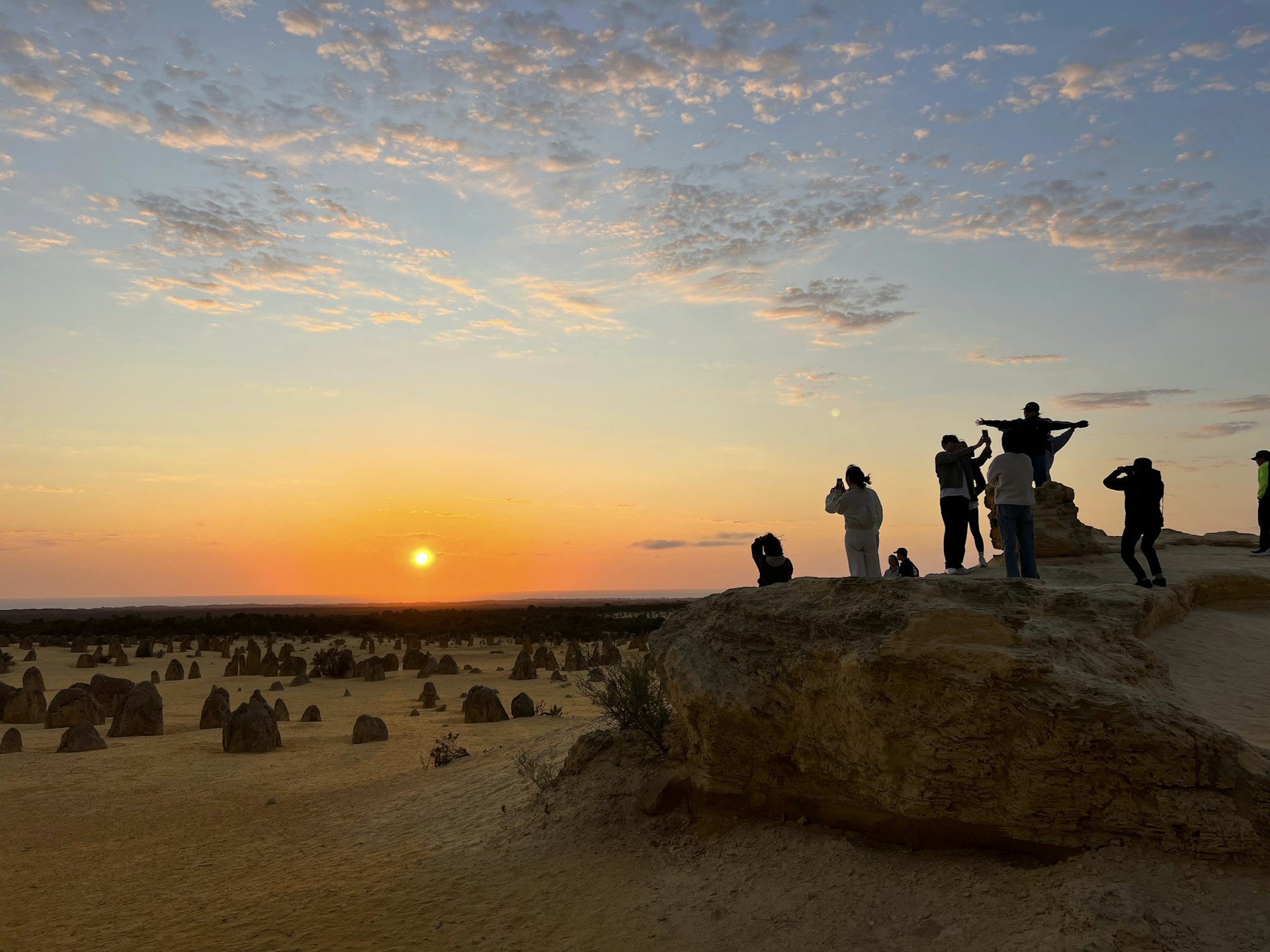 A group of tourists take photos at The Pinnacles at sunset