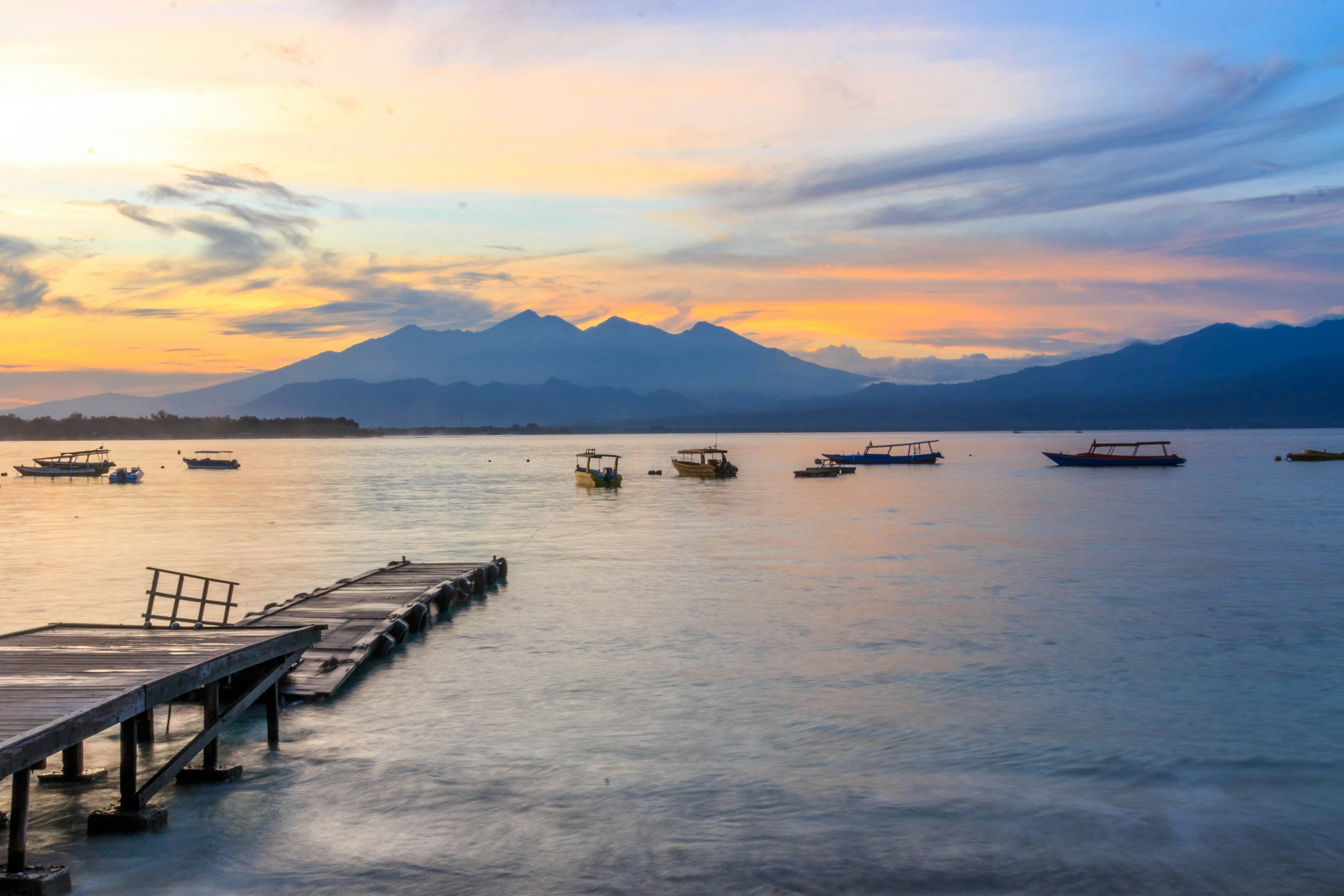 Seas with jetty and mountain range in background,