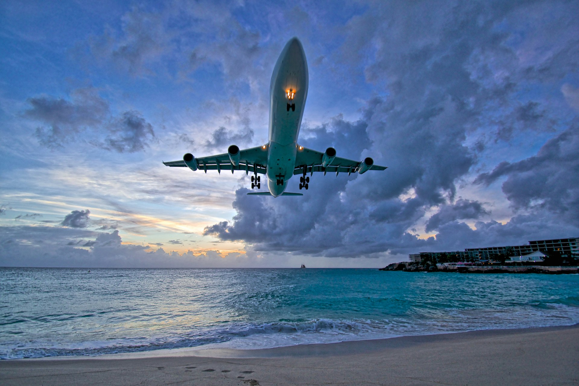 A plane comes in to land very low over a beach