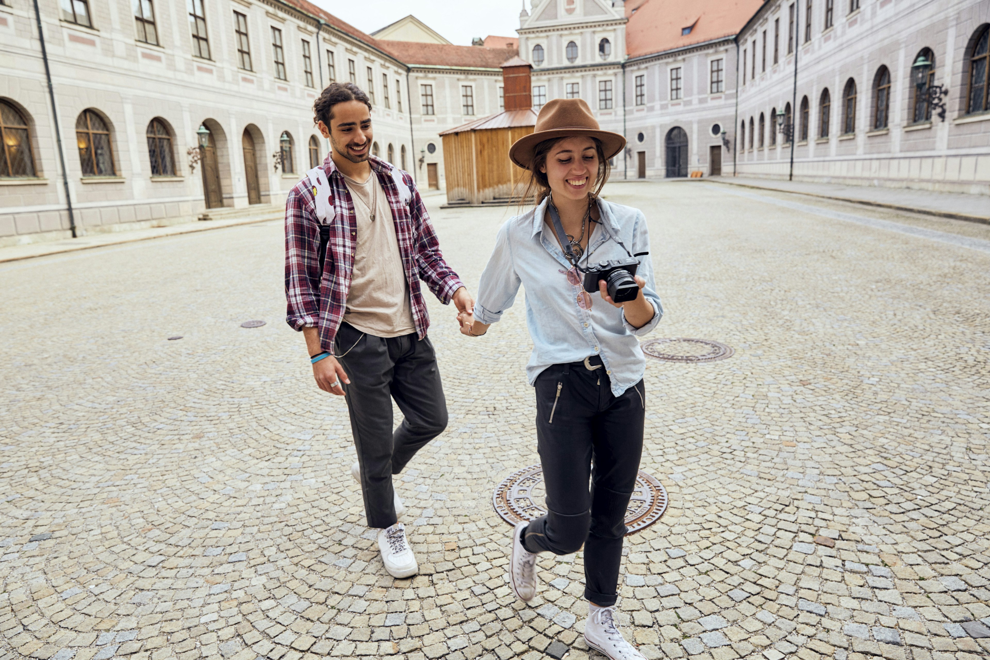 A woman and man holding hands while walking through Munich