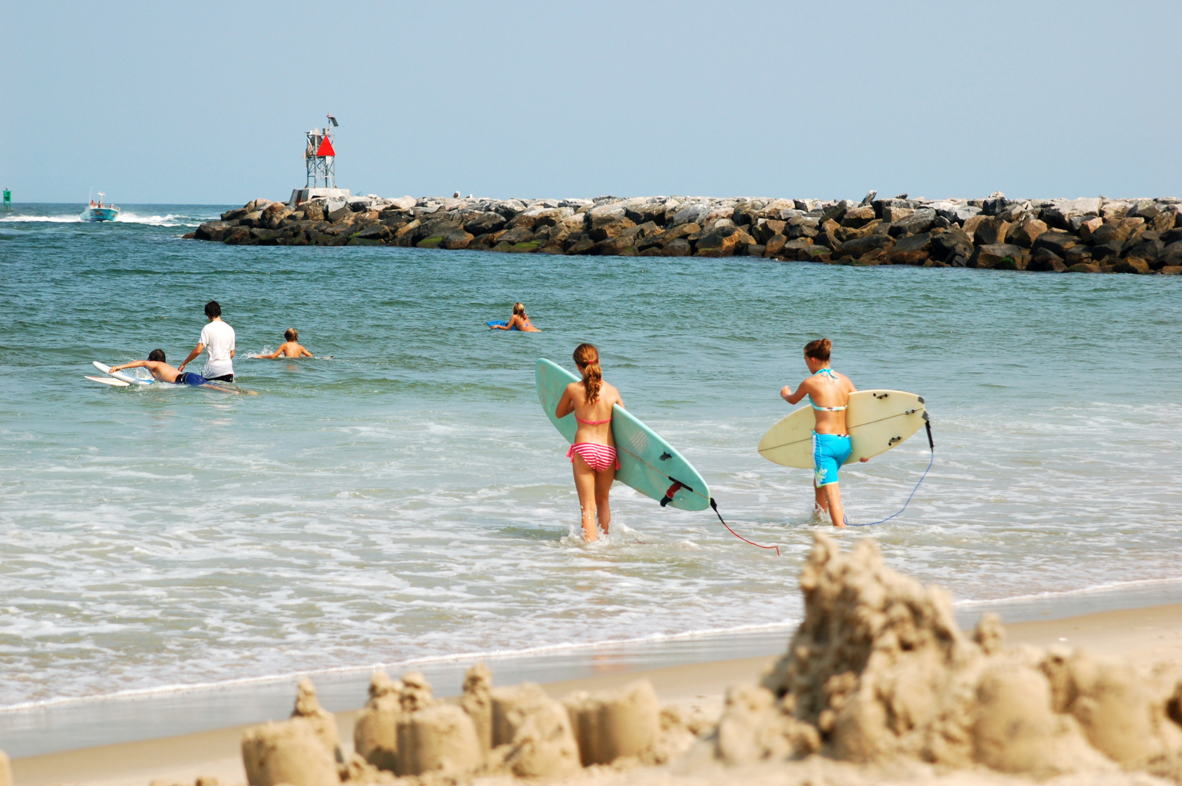 Two girls walk into the water with surfboards at Virginia Beach