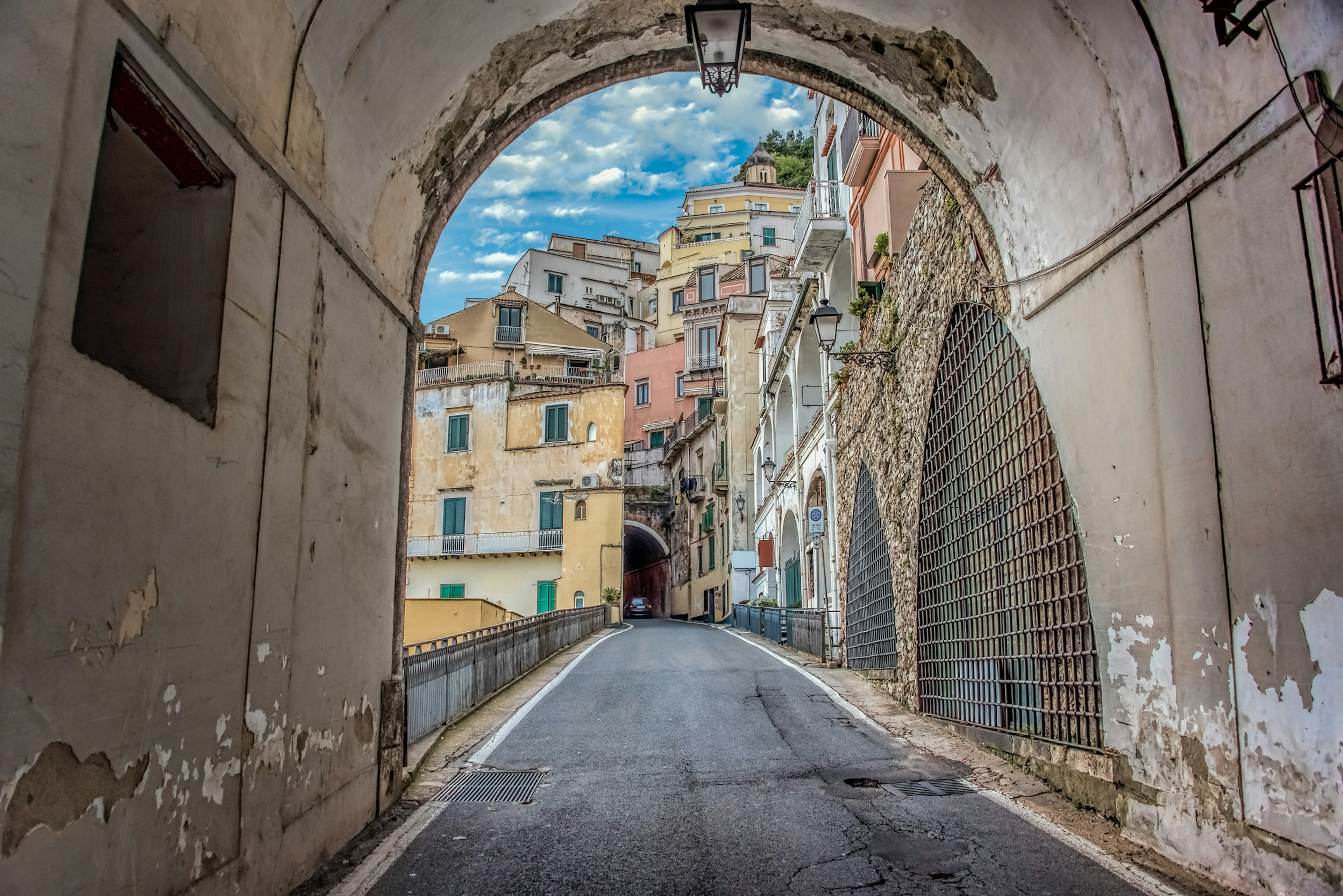 A car winds up a narrow road between tightly packed buildings