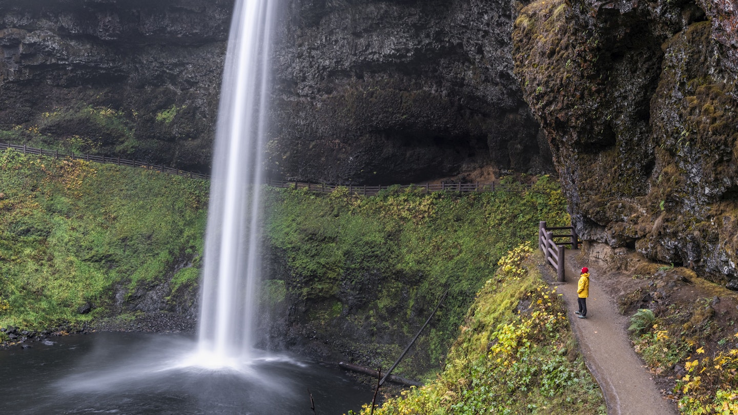 Female tourist with red hat and yellow jacket staring at South Falls in autumn, Silver Falls State Park, OR, US.
1189512563