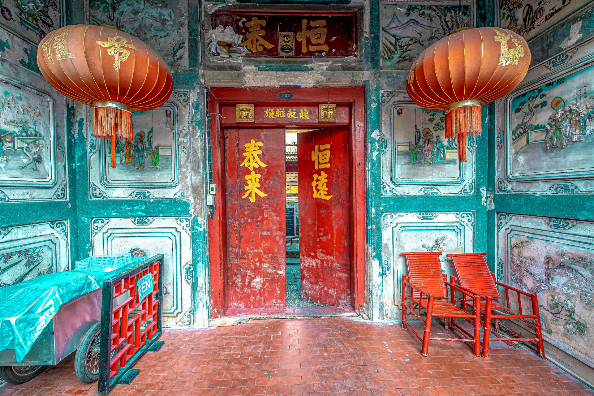 A Chinese-style temple door with red lanterns hanging either side of it