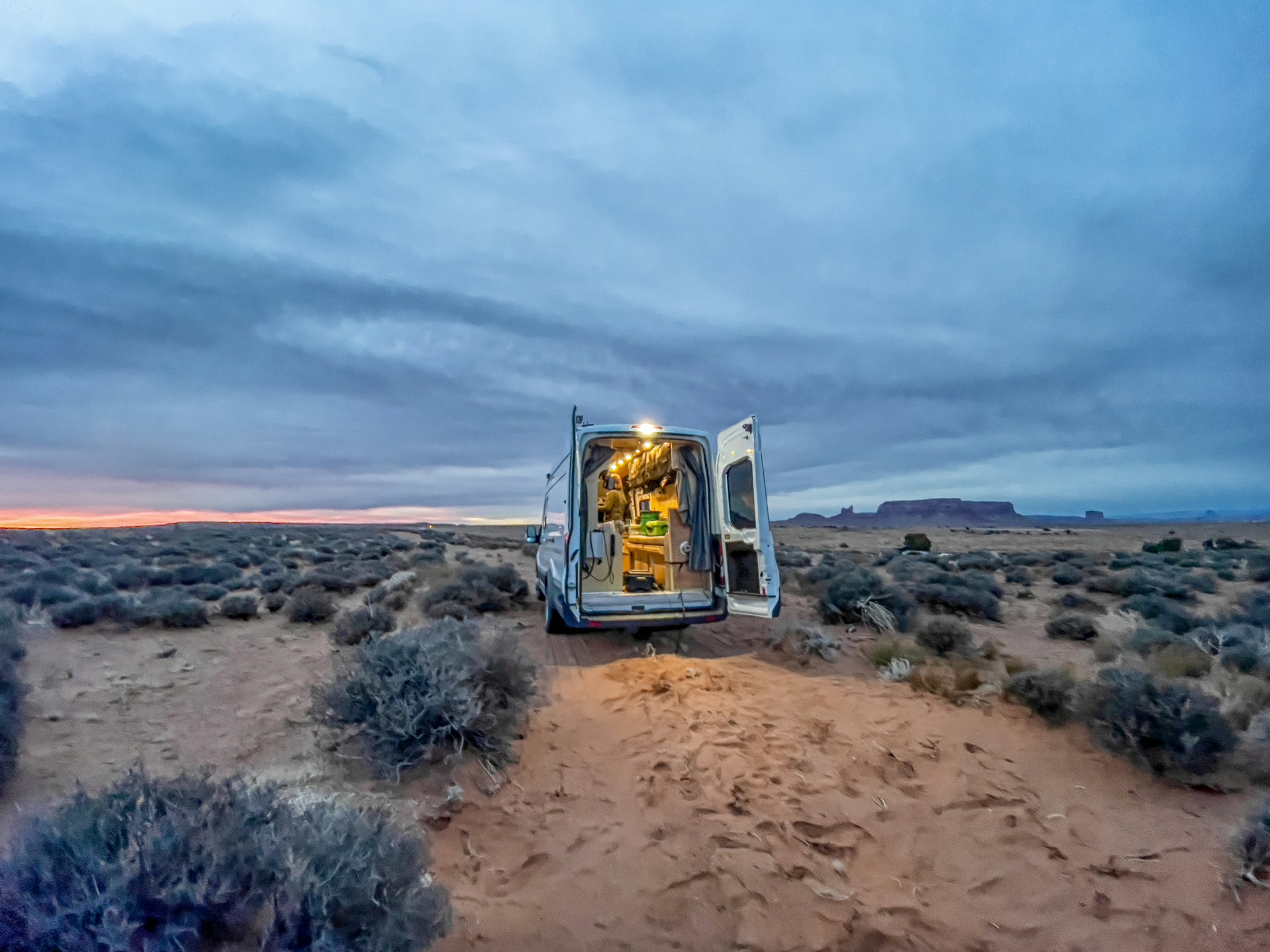 A camper van with open rear doors in the Monument Valley Desert, Utah & Arizona, USA
