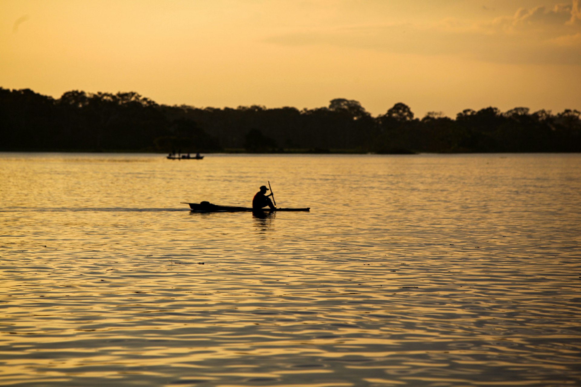 A fisherman paddles on the Amazon River at sunrise
