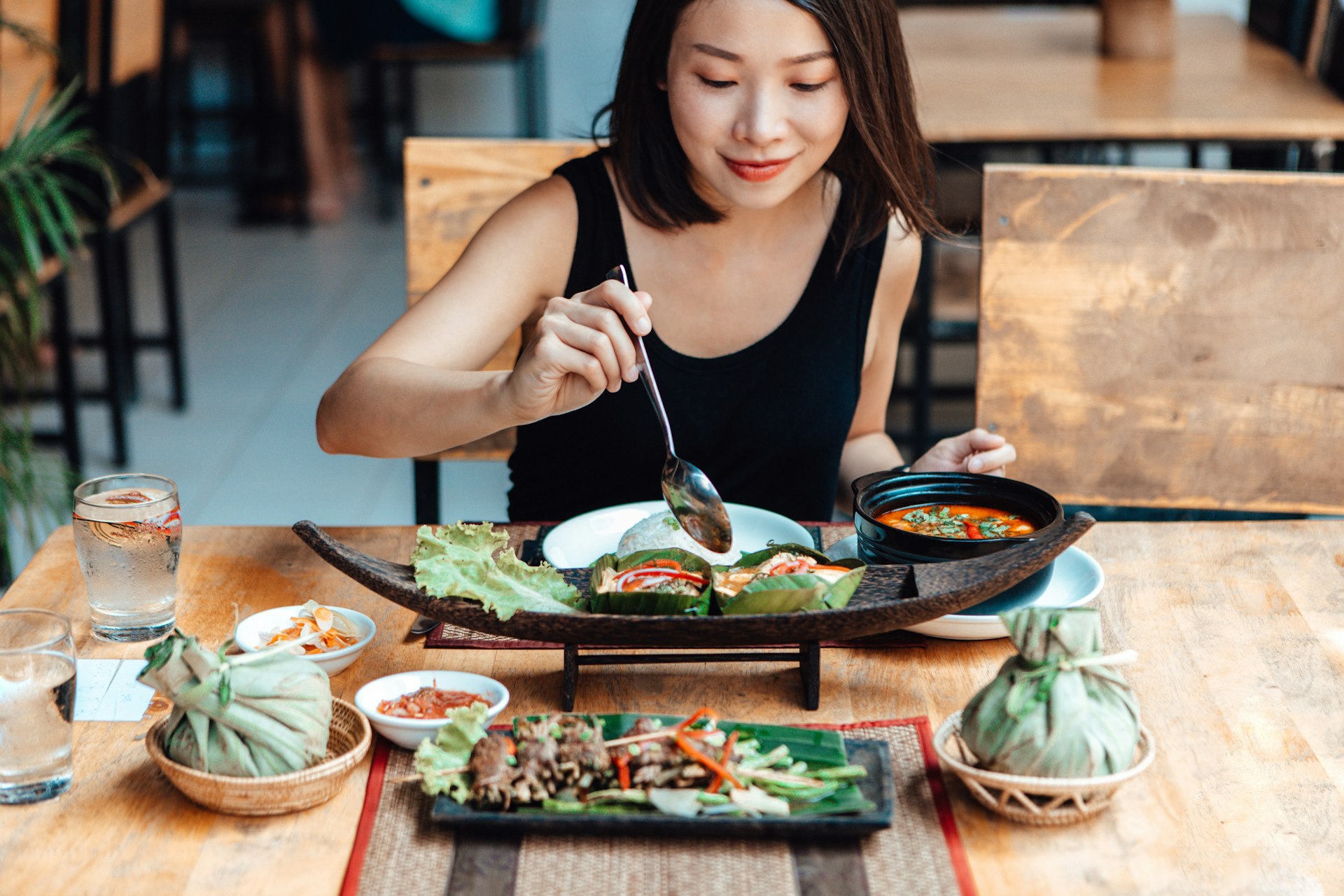 Close up shot of young Asian woman having freshly made authentic Thai food in a Thai restaurant