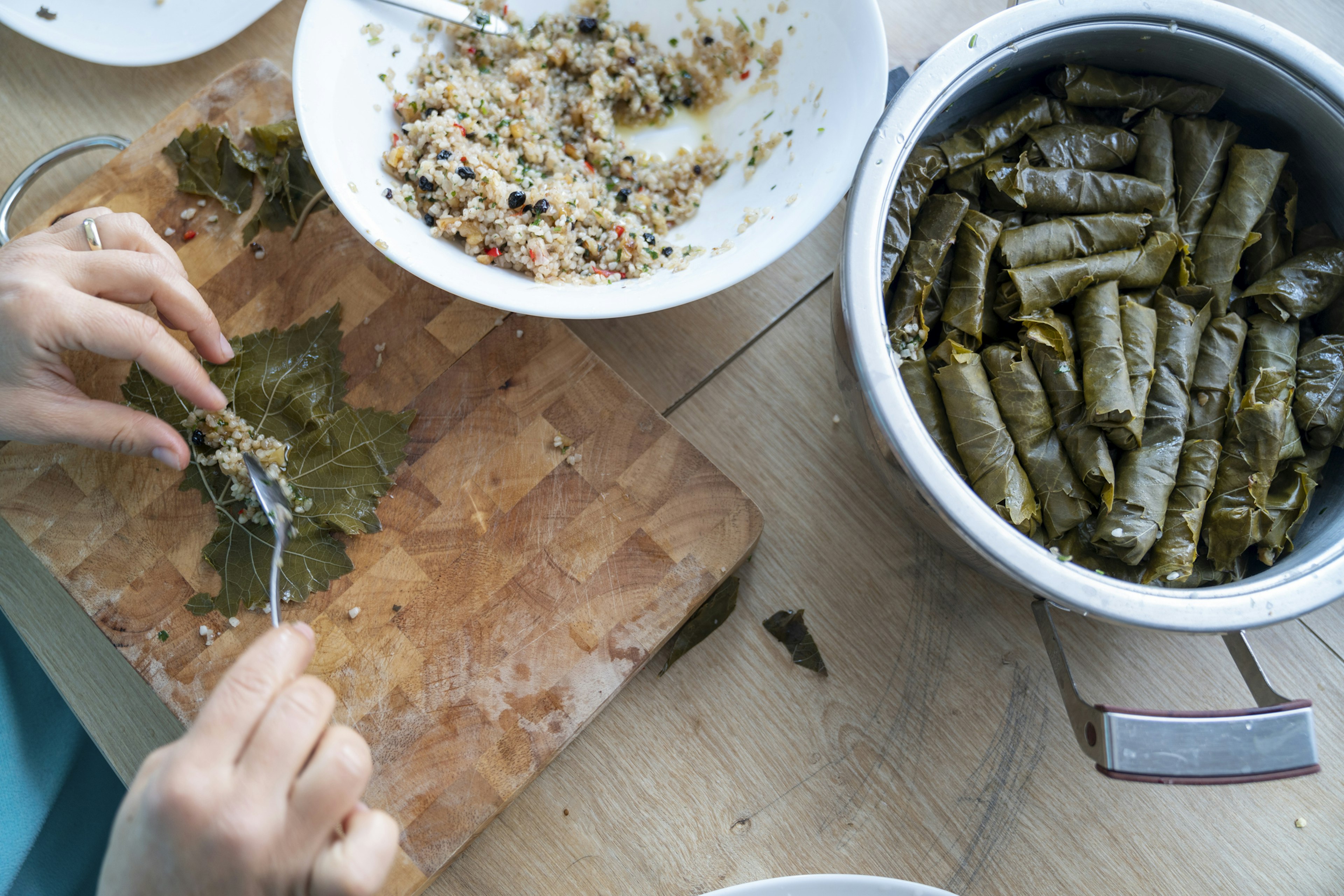 Close up photo of hands preparing stuffed vine leaves