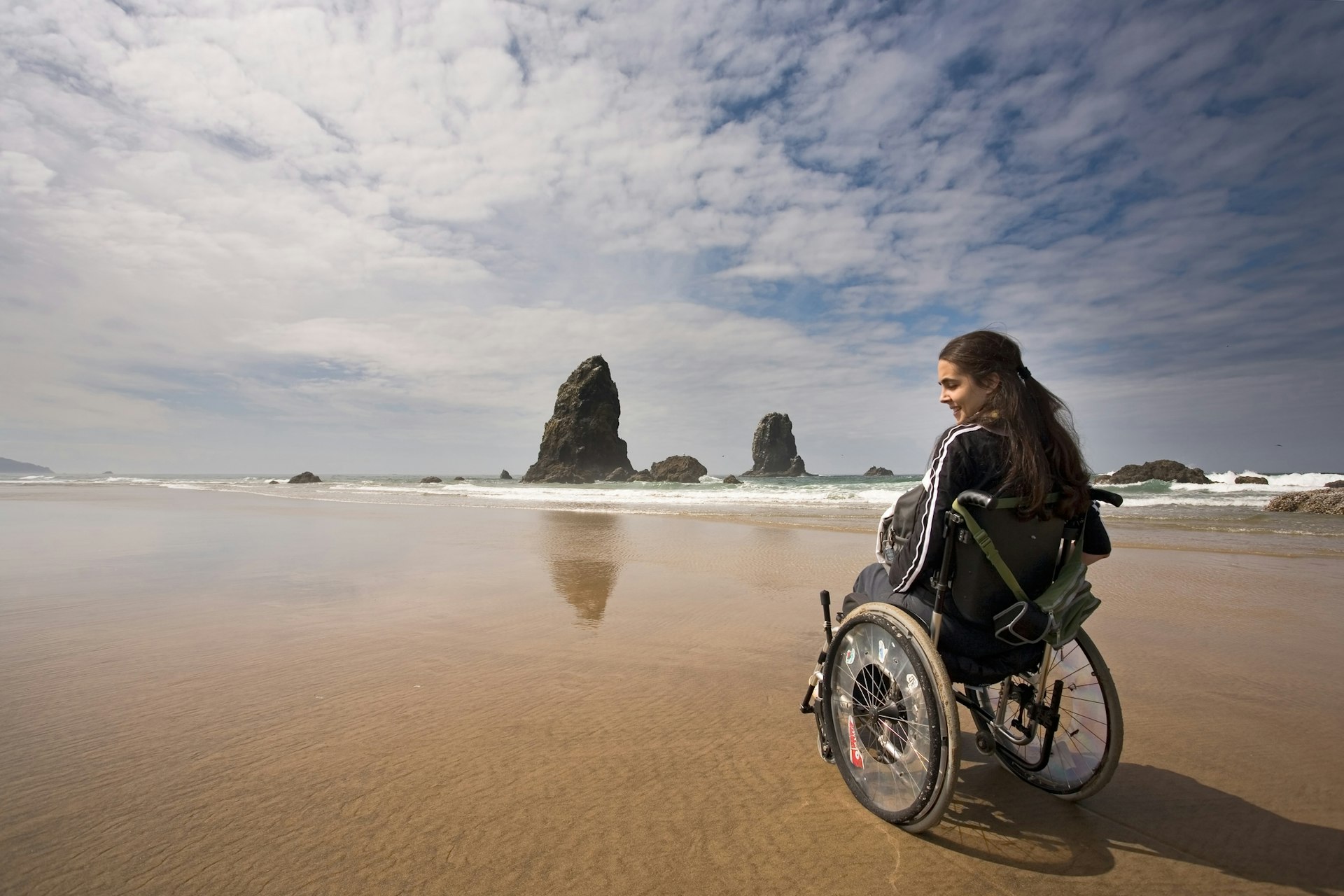 Wheelchair user admires the view at Canon Beach, Oregon, USA
