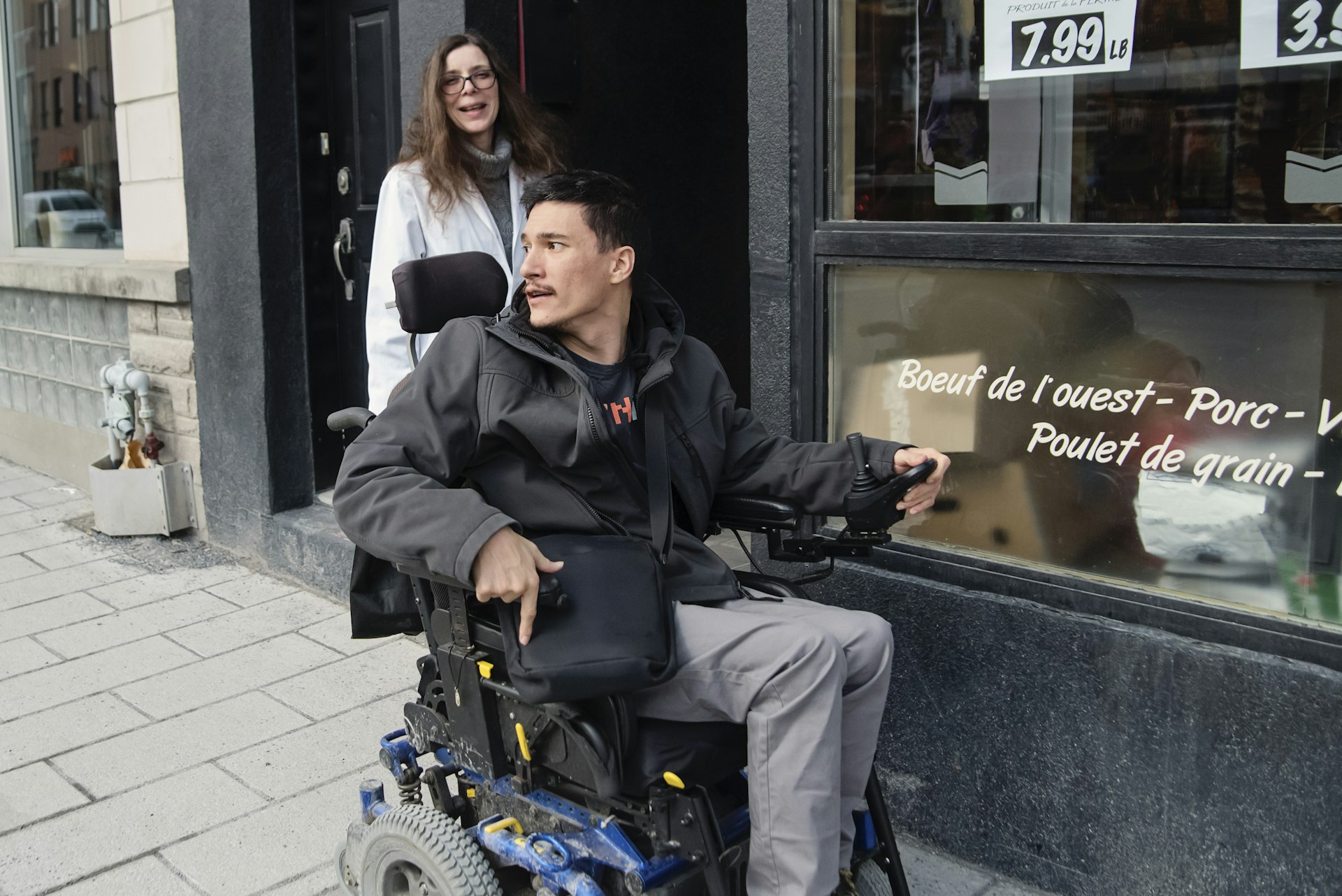 Young man using motorized wheelchair to get out of a store, Montréal, Québec, Canada