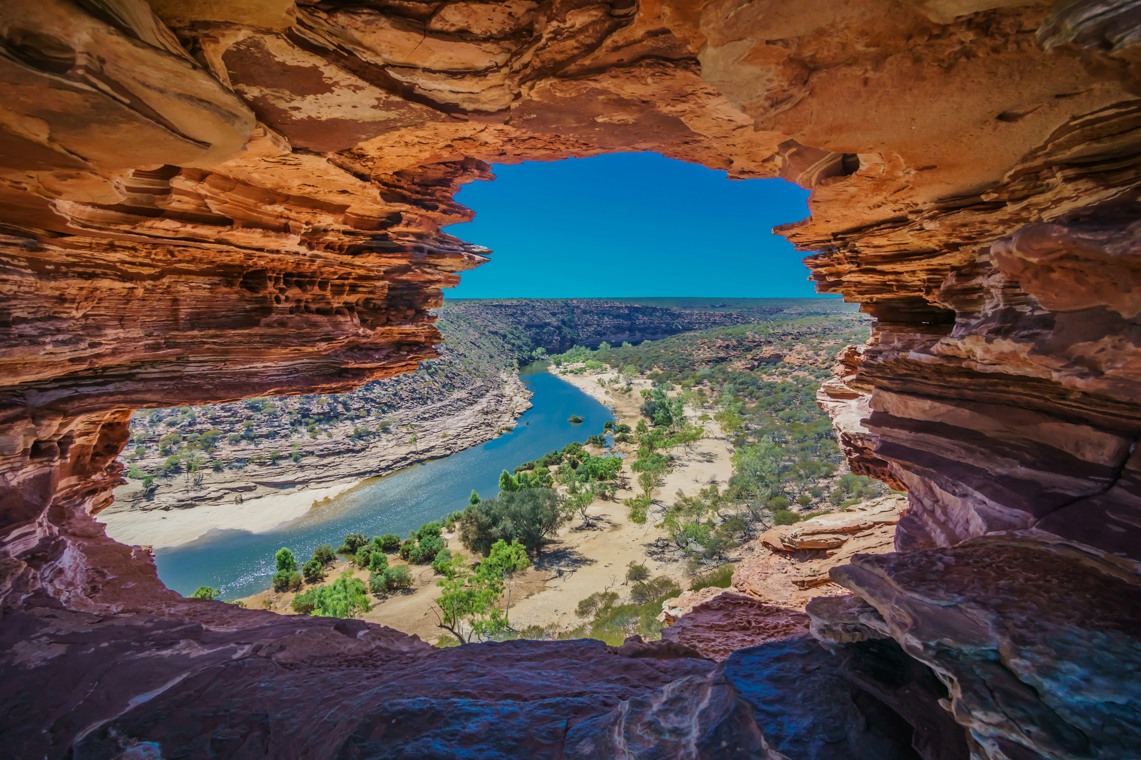A river runs through a gorge with dramatic red-rock formations