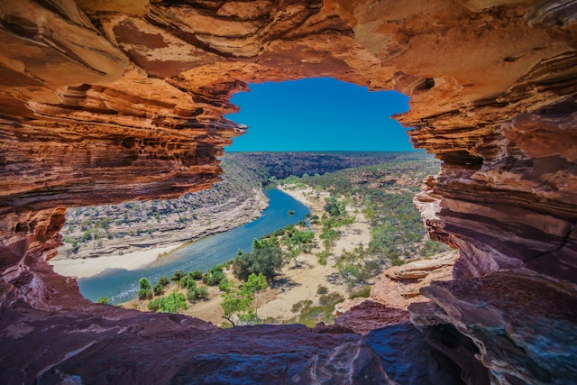 A river runs through a gorge with dramatic red-rock formations