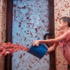 A reveller uses a bucket to hurl crushed tomatoes during the "Tomatina" annual food-battle in the Spanish eastern town of Bunol, on August 30, 2023. Around 15,000 people, gathered today in Spain's annual "Tomatina" street battle to hurl each other 120 tons of tomatoes. (Photo by Jose Miguel FERNANDEZ / AFP) (Photo by JOSE MIGUEL FERNANDEZ/AFP via Getty Images)
1634191942
festival, Horizontal