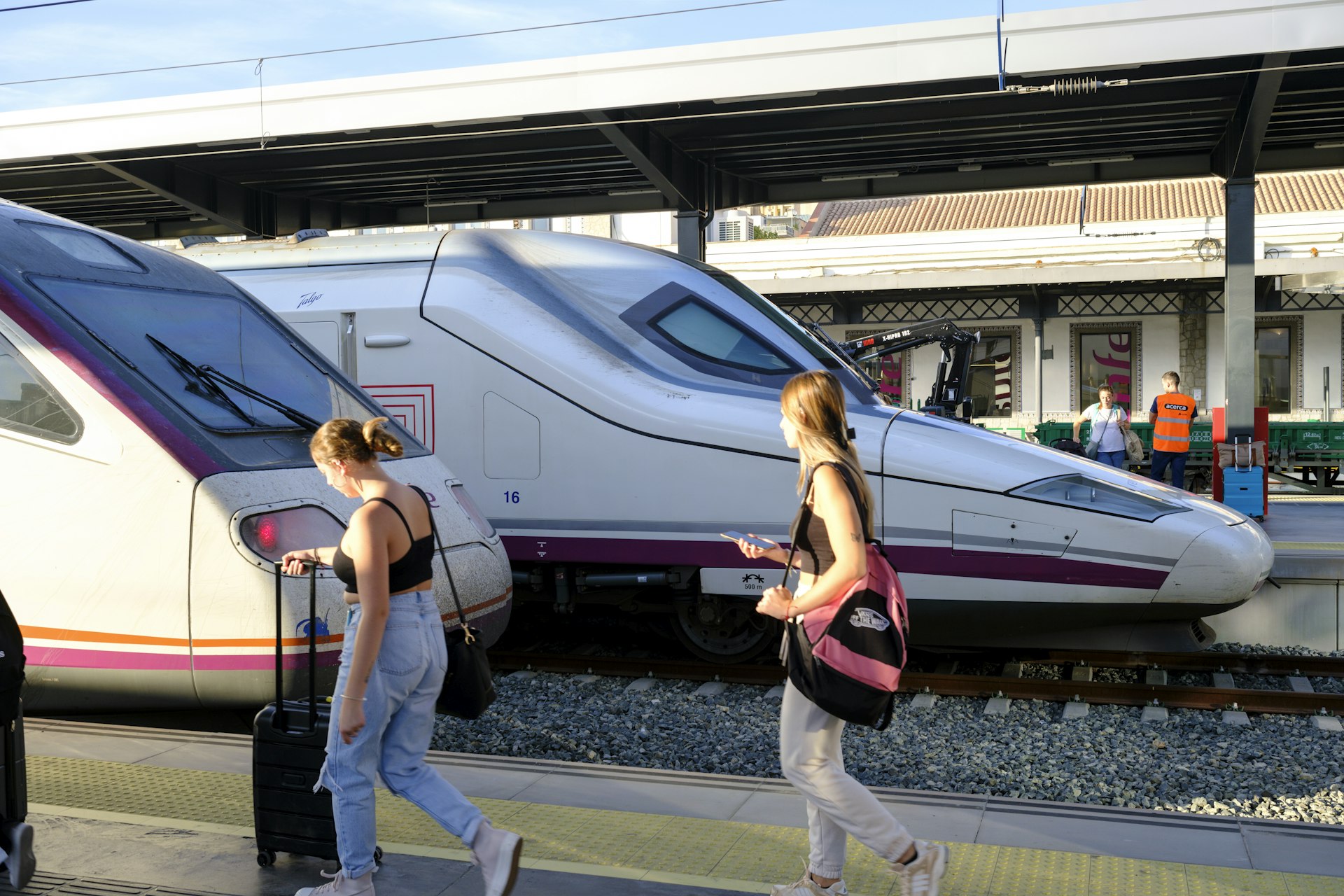 Two young women with suitcases board a Renfe train in Granada