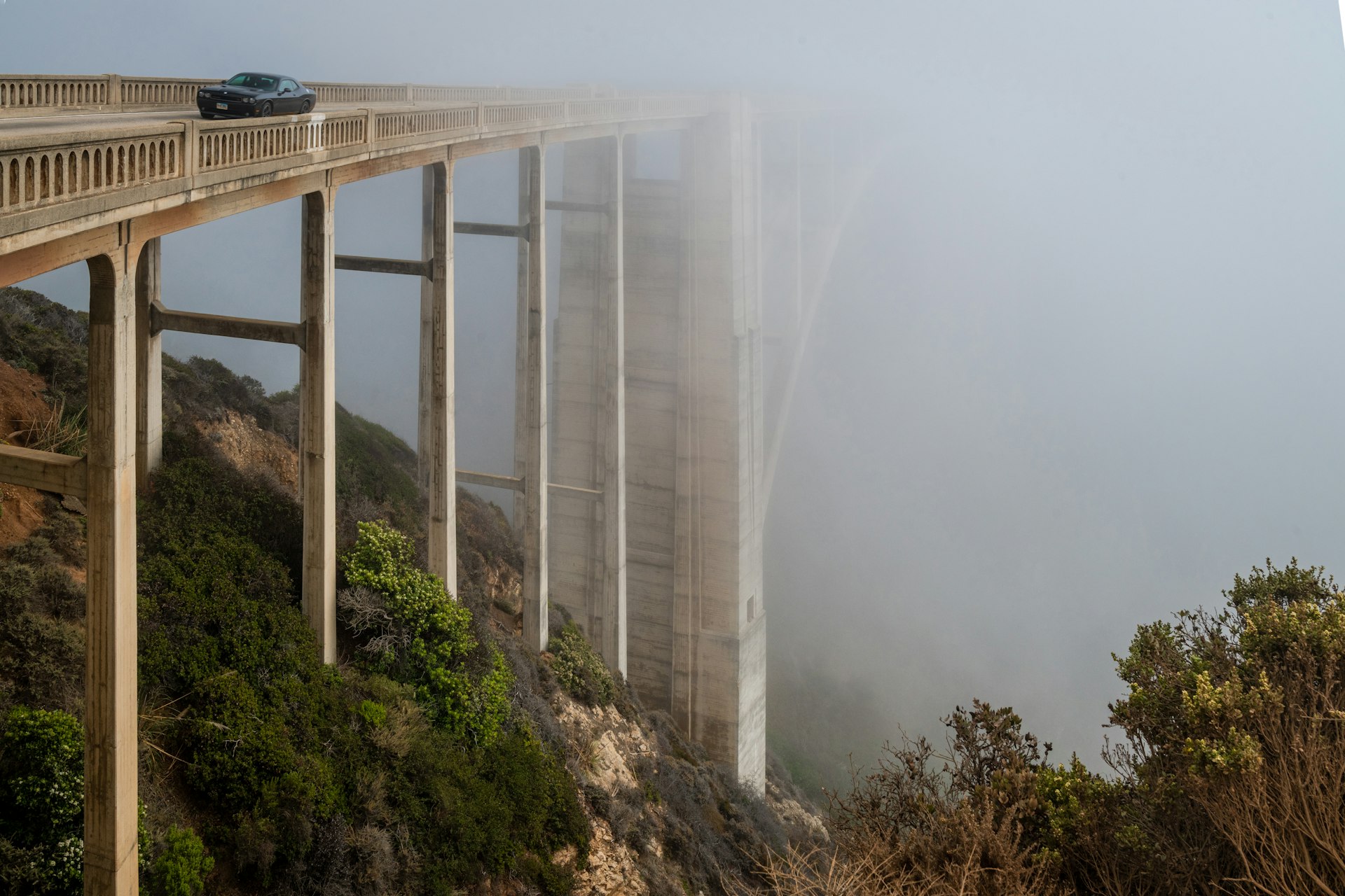 Um carro atravessa a ponte Bixby em condições de neblina, Big Sur, Califórnia, EUA
