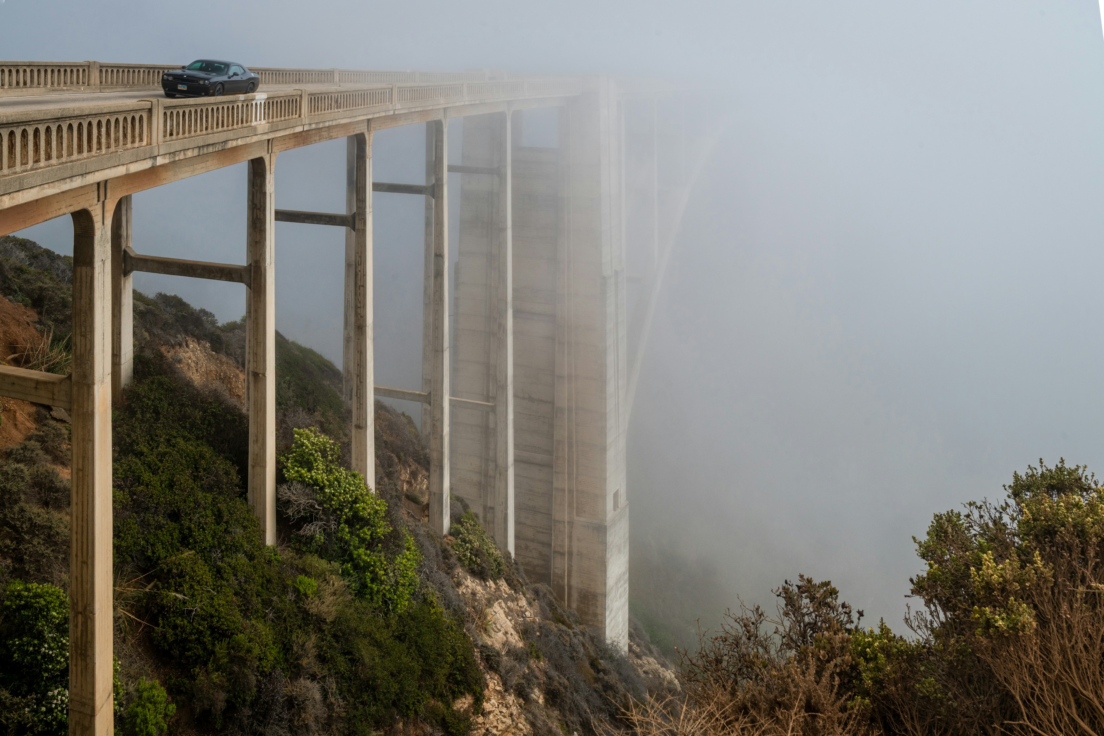 A car drives across Bixby Bridge in foggy conditions, Big Sur, California, USA