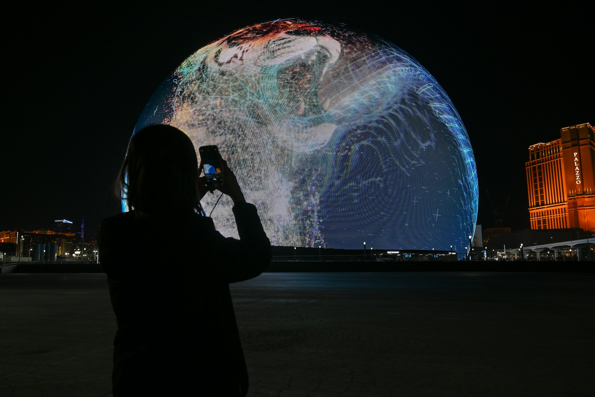 A person takes a photo of the illuminated Sphere venue in Las Vegas