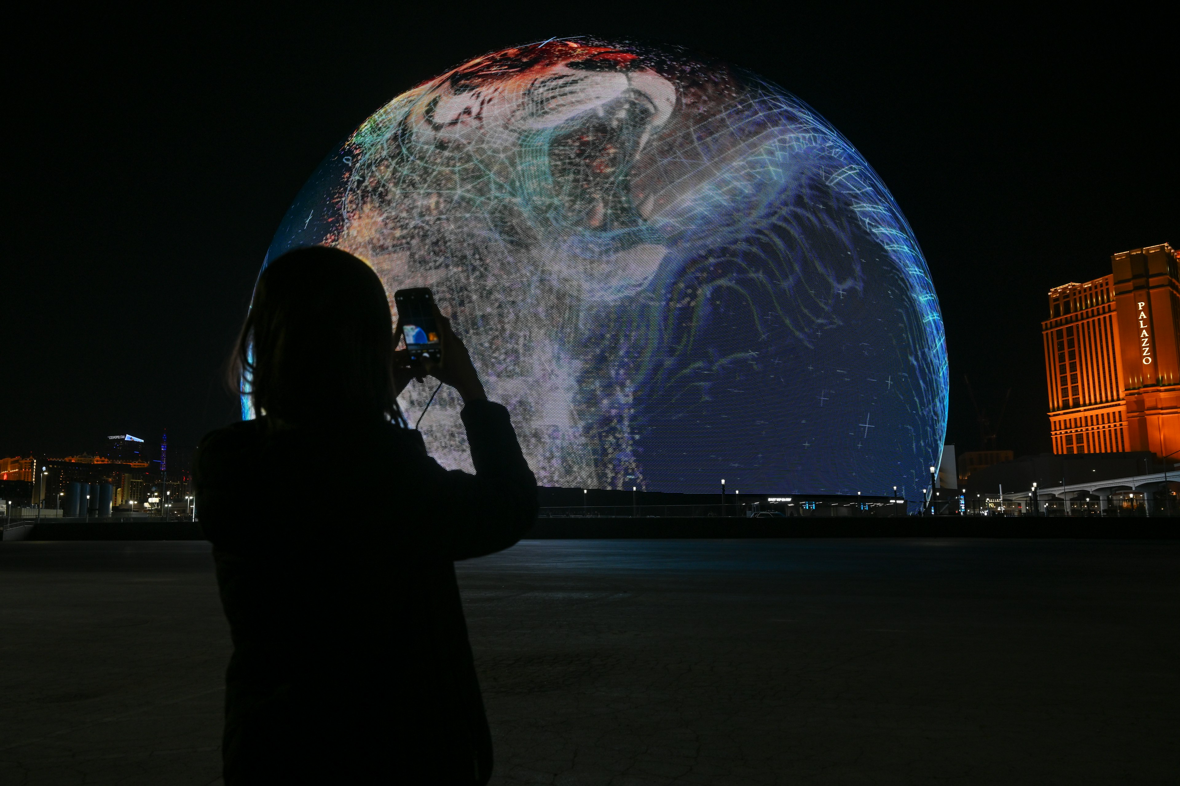 A person takes a photo of the illuminated Sphere venue in Las Vegas