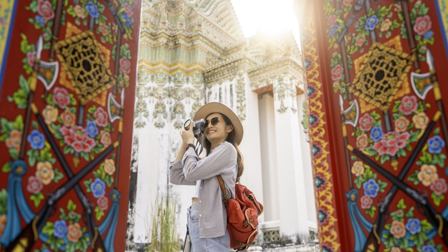 A woman taking a picture of Wat Pho in Bangkok