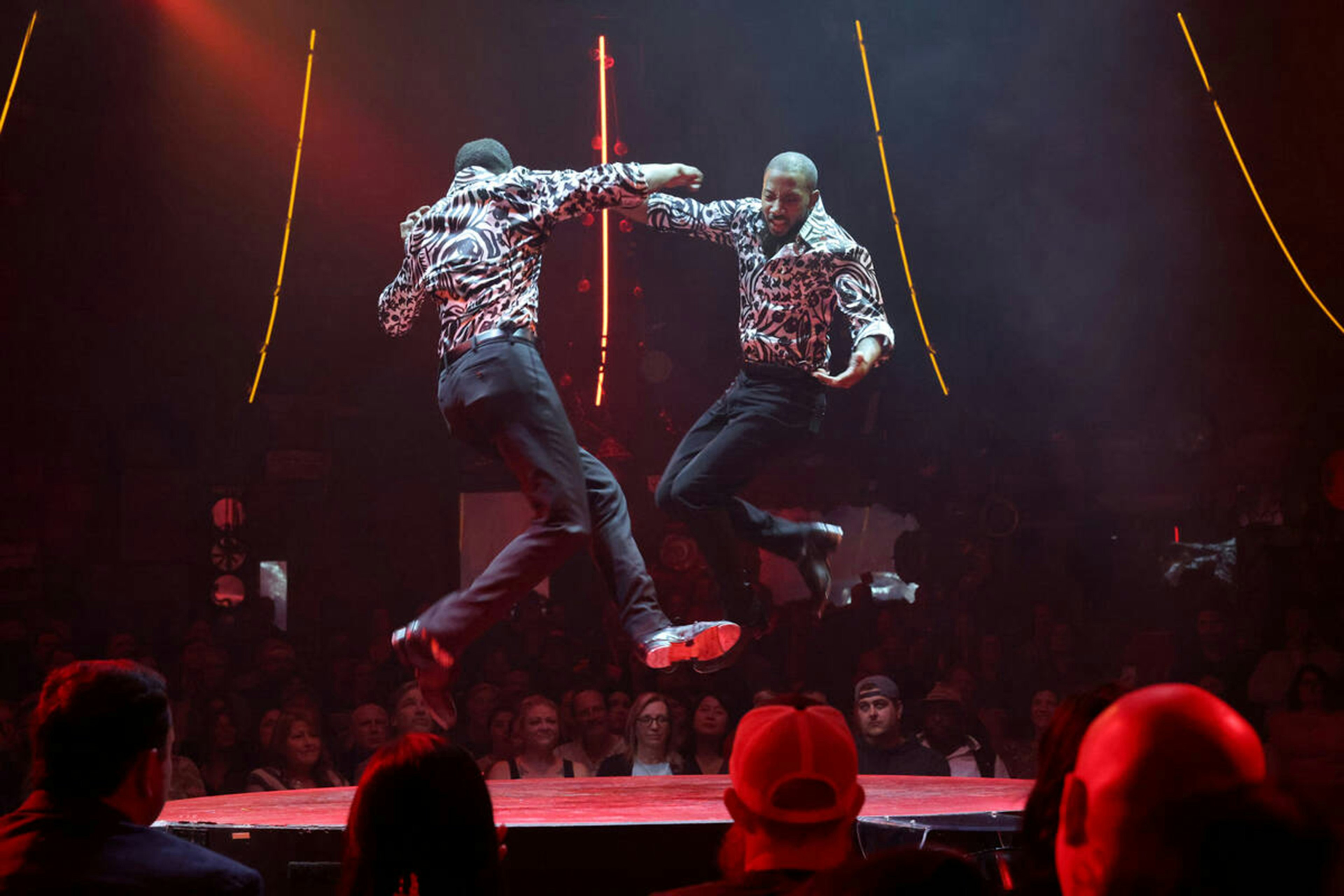 Twin brothers Sean and John Scott tap dance on a small circular stage during