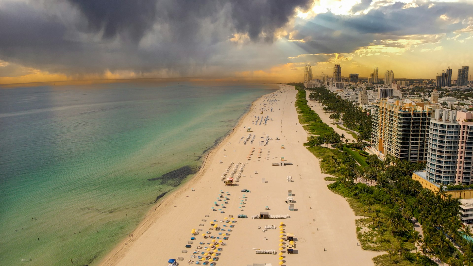 An arial view of Miami Beach in June, with dark gray rain clouds looming in the sky