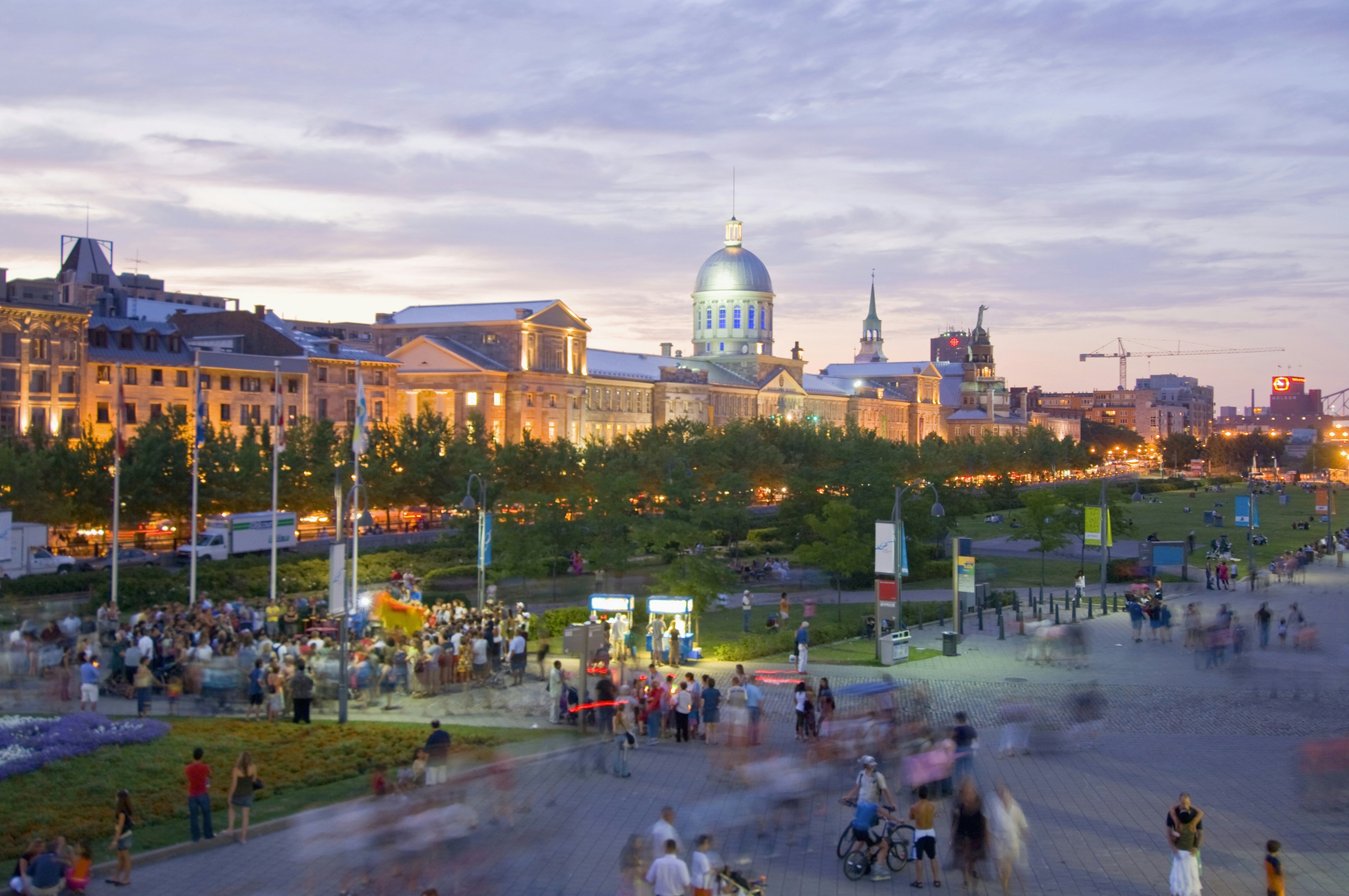 Crowds of people on an open square in front of a large municipal building at dusk