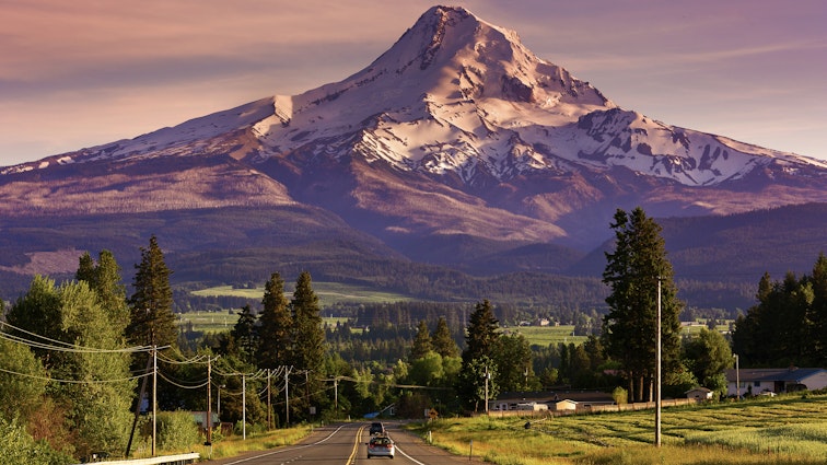 Route 35 leading to snow-covered Mount Hood, Oregon, at sunset, with two cars on road.
561511141