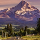 Route 35 leading to snow-covered Mount Hood, Oregon, at sunset, with two cars on road.
561511141