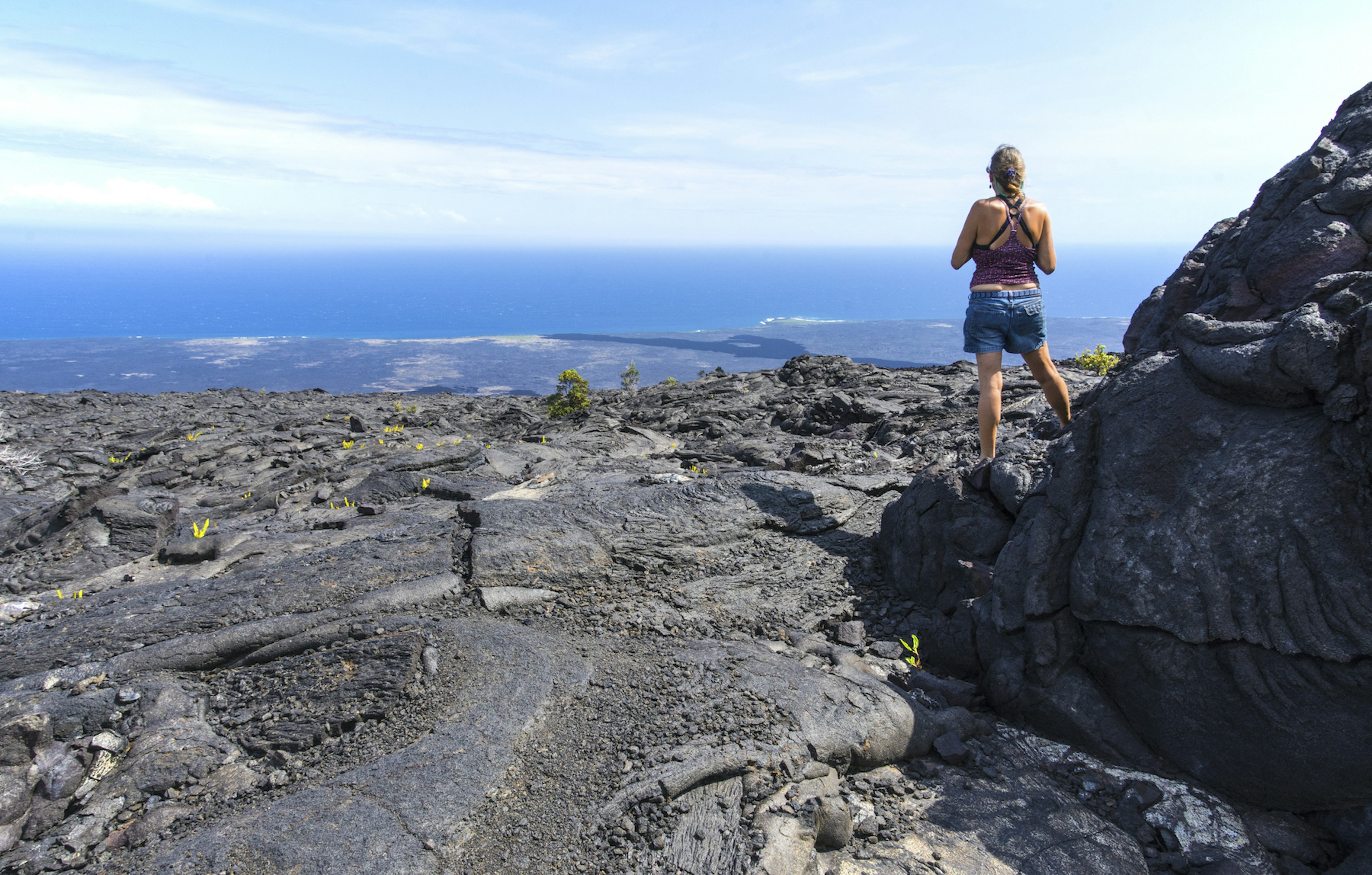 Woman viewing the Pacific Ocean from a scenic point along the Chain of Craters Road. Hawaii Volcanos National Park