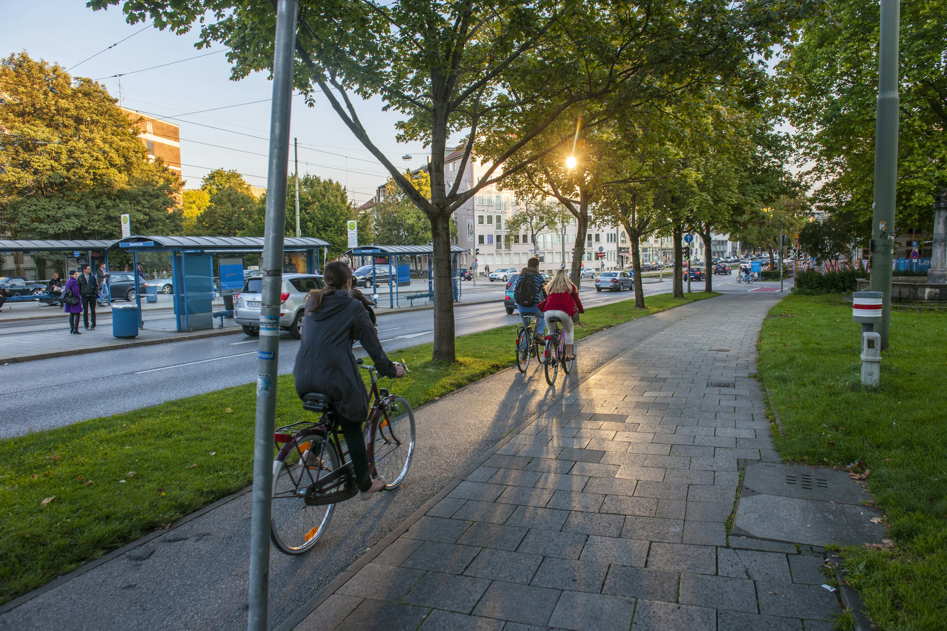 Cyclists passing with trams in the backgroun in the afternoon in Munich