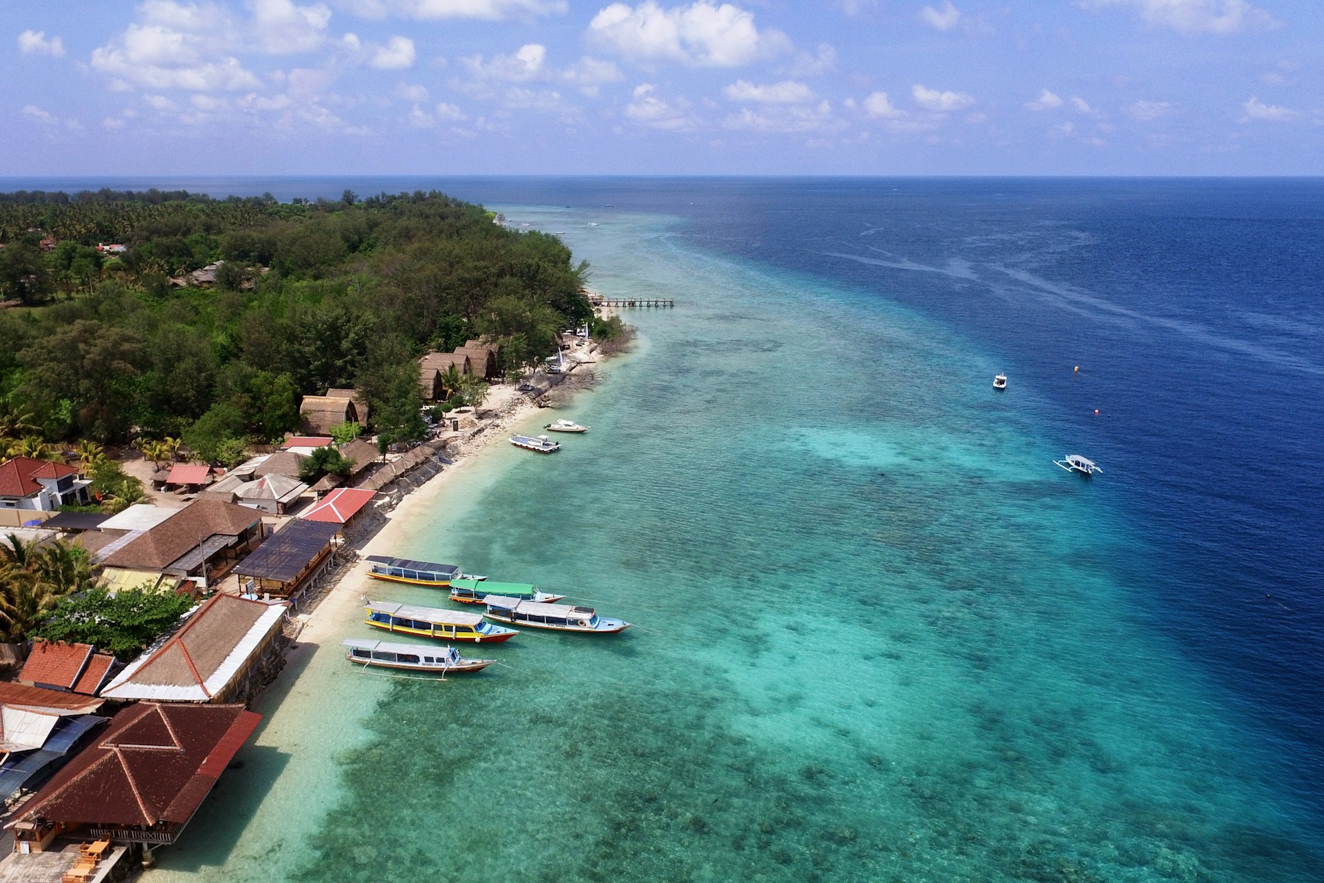 An aerial shot of ferry boats on a beach in the Gili Islands