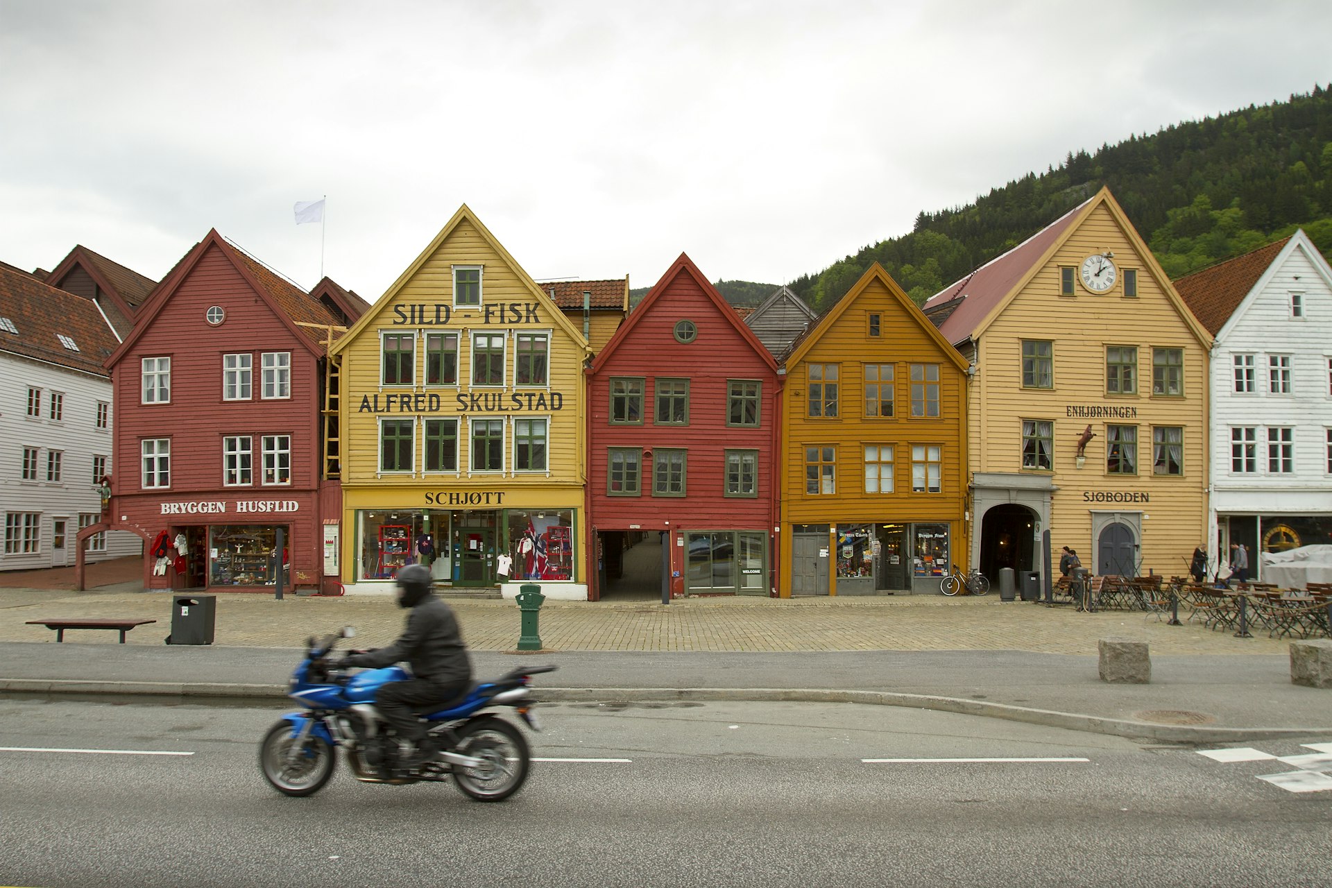 A motorcyclist passes the colorful buildings of Bryggen in Bergen, Norway
