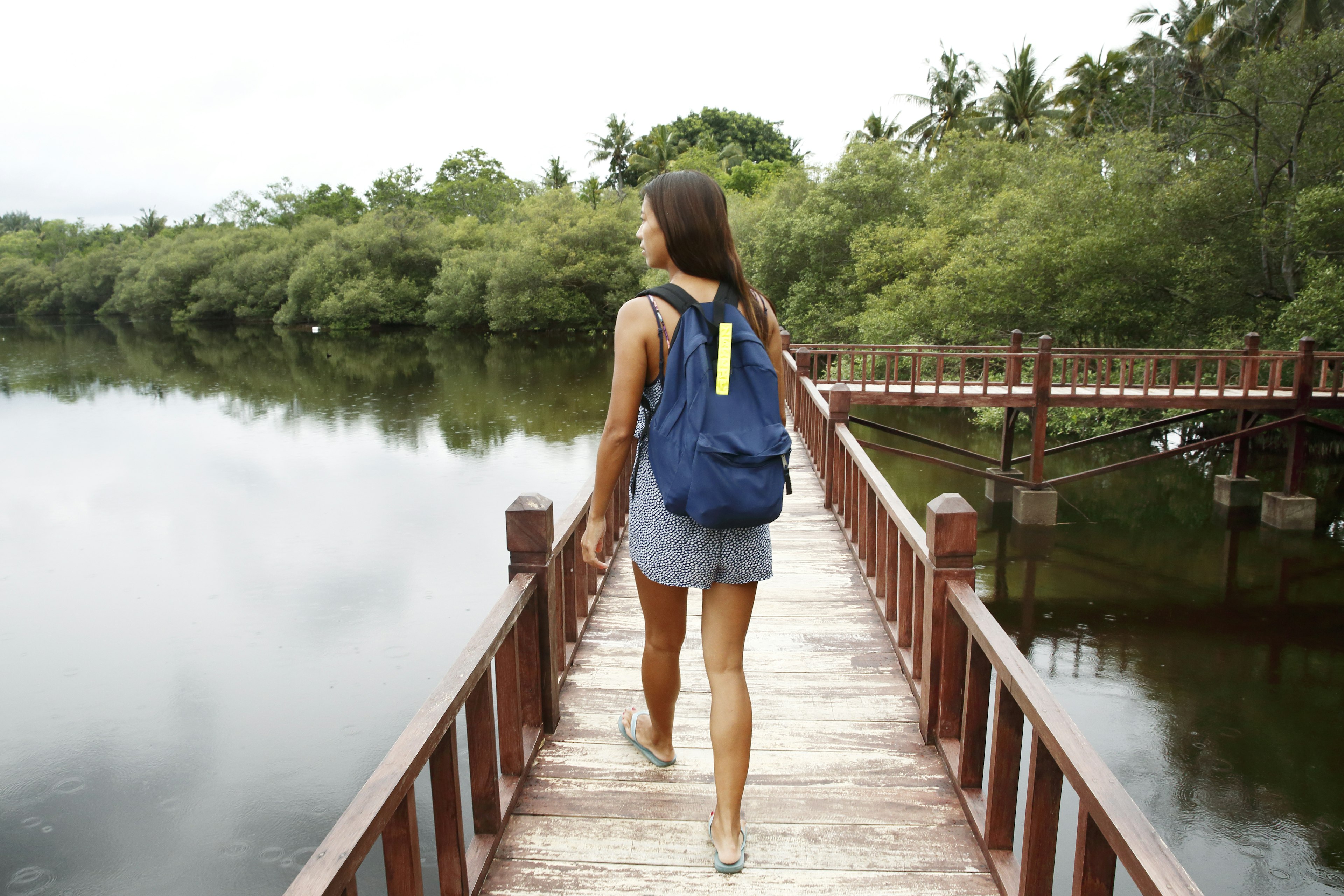 A woman walks on a boardwalk over water in the Gili Islands