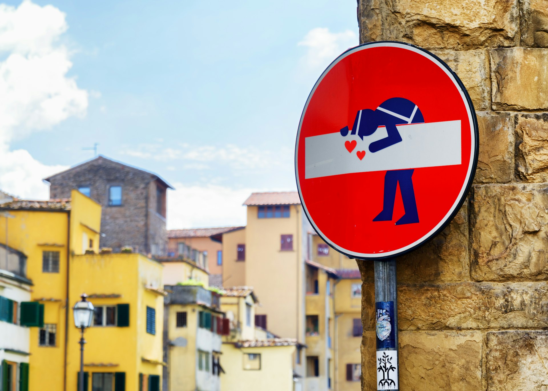 A circular no entry sign that has been altered by a street artist to include a cartoon of a police officer.