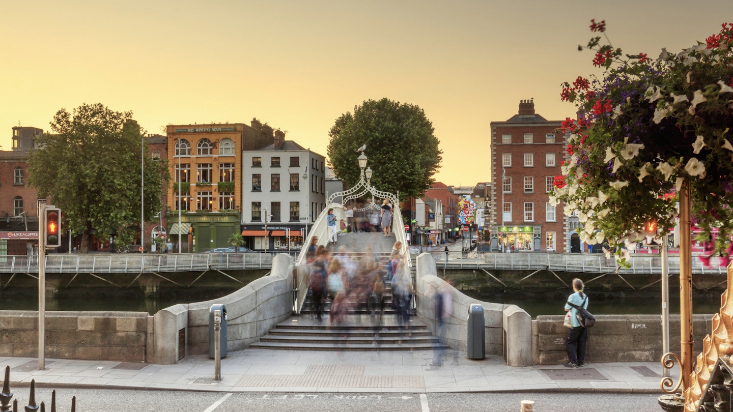 People walking across the Ha'penny bridge in Dublin City at sunset
865636254