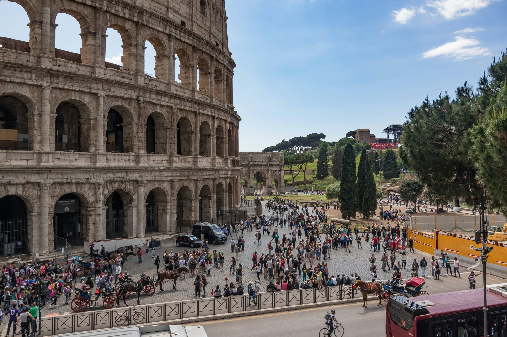 Lots of people gathered around the outside of an ancient amphitheater