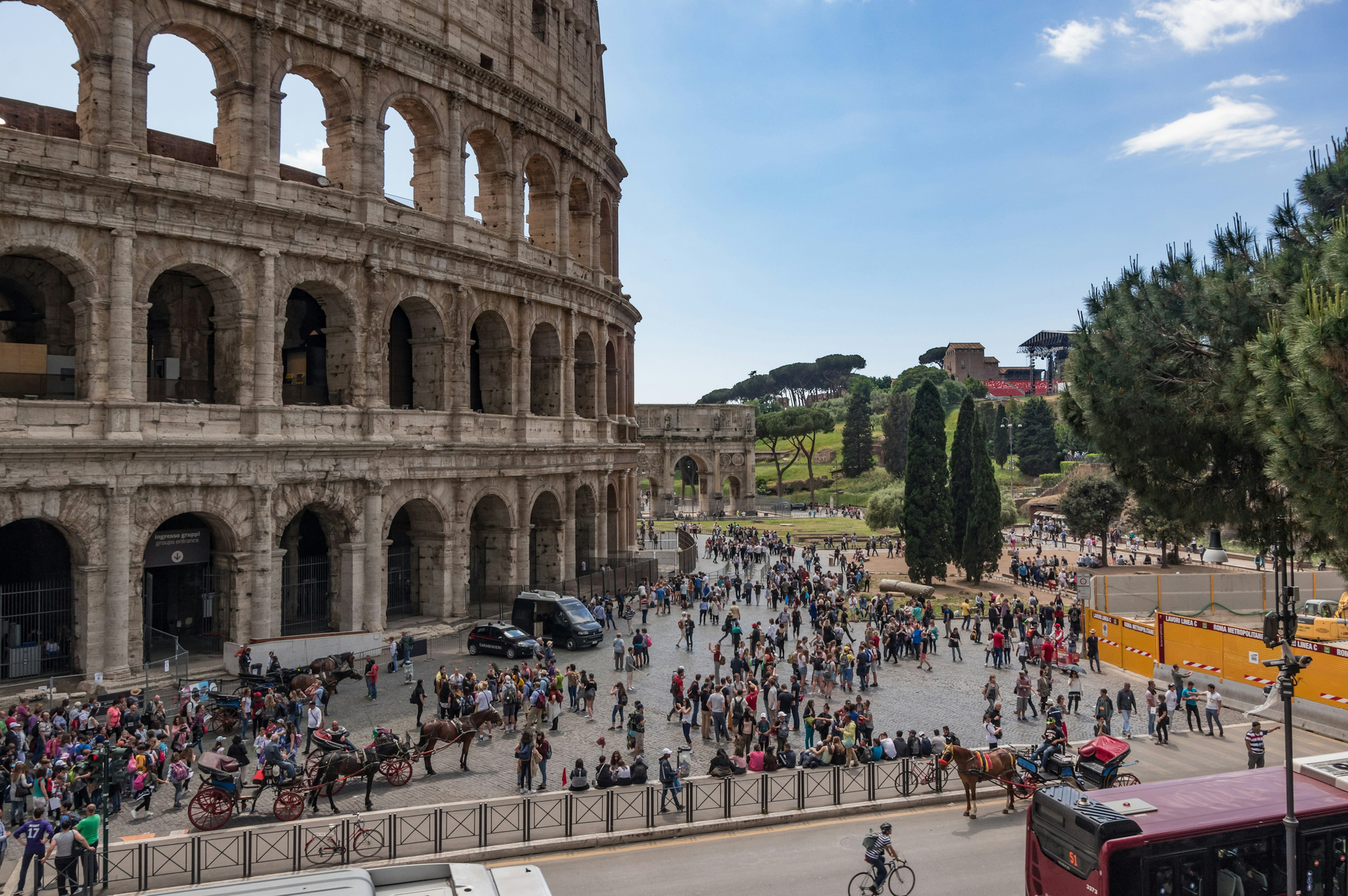 Lots of people gathered around the outside of an ancient amphitheater