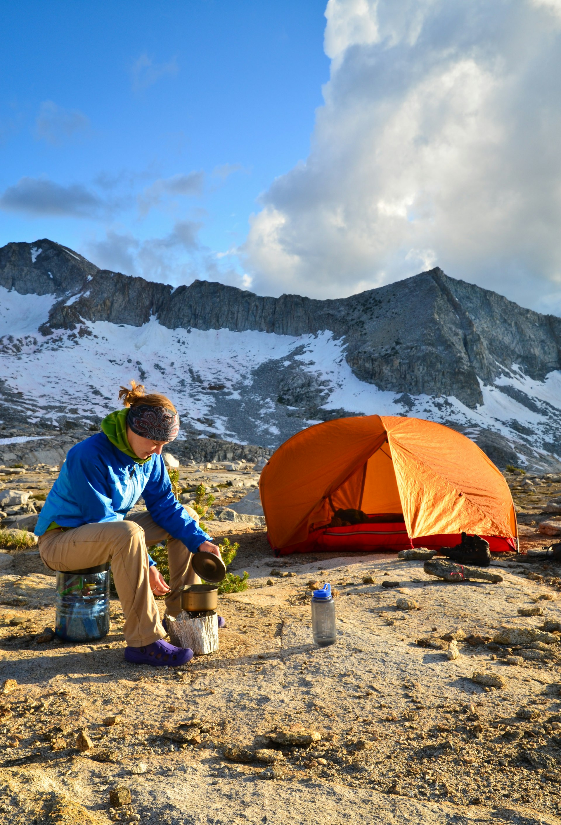 Woman sitting next to pitched tent at snow-capped Sierra Nevada