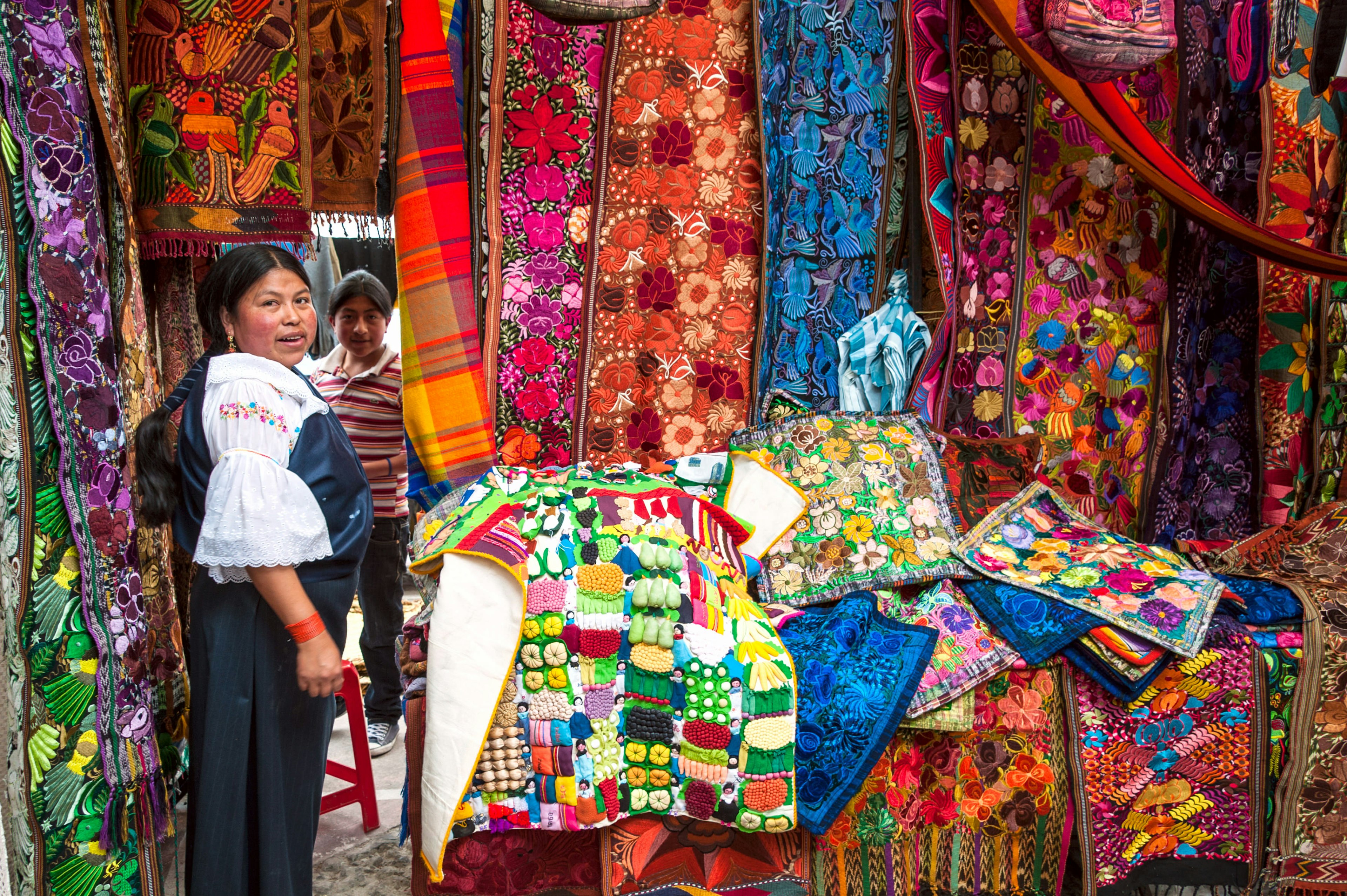 Ecuadorian women in national clothes sells the products of his weaving, as usual on weekdays on a market in the Otavalo