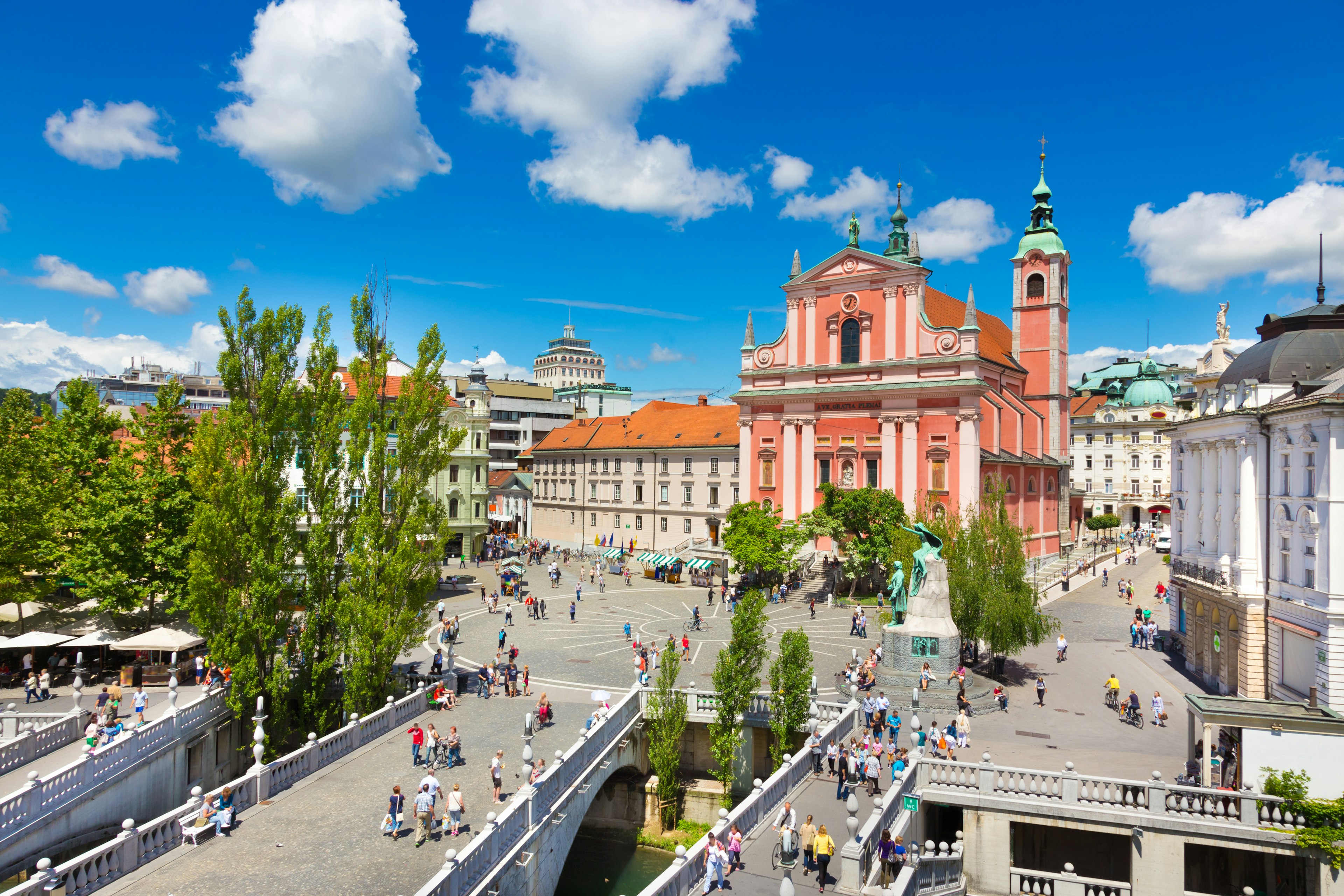 The red facade of a building dominates a city square near a river