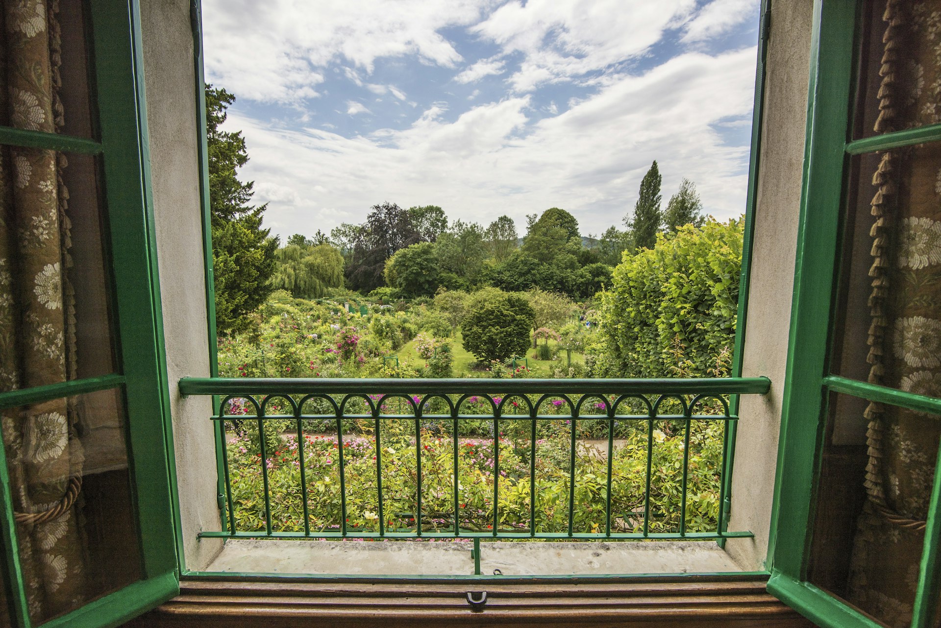 Beautiful garden blooms viewed through a large window with an ornate wrought-iron rail 