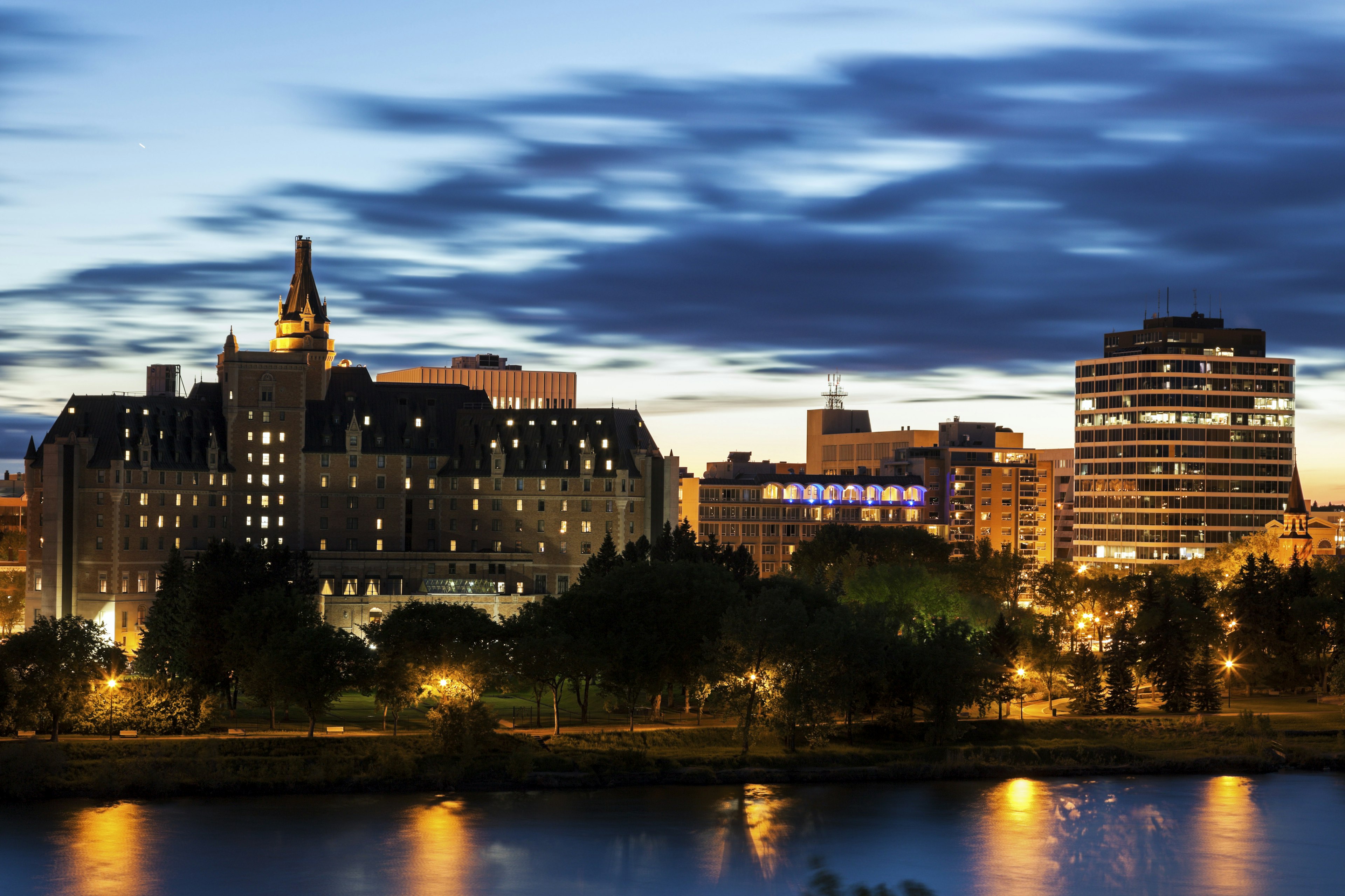 The night sky glows behind some riverside buildings following sunset